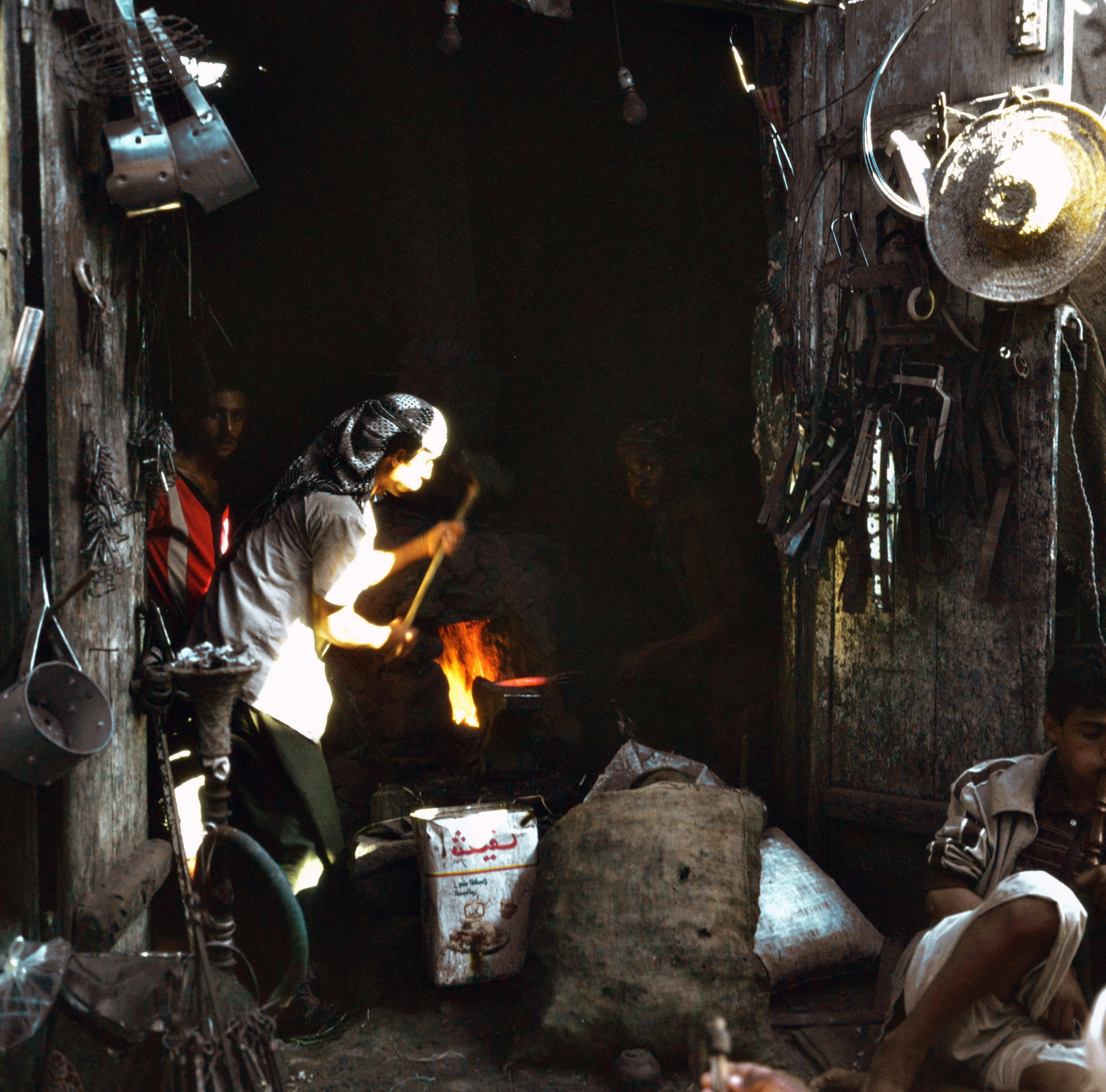 Blacksmith working at a forge with tools around.
