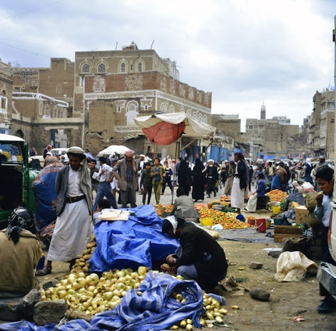 Bustling marketplace with people and goods in a historic city.