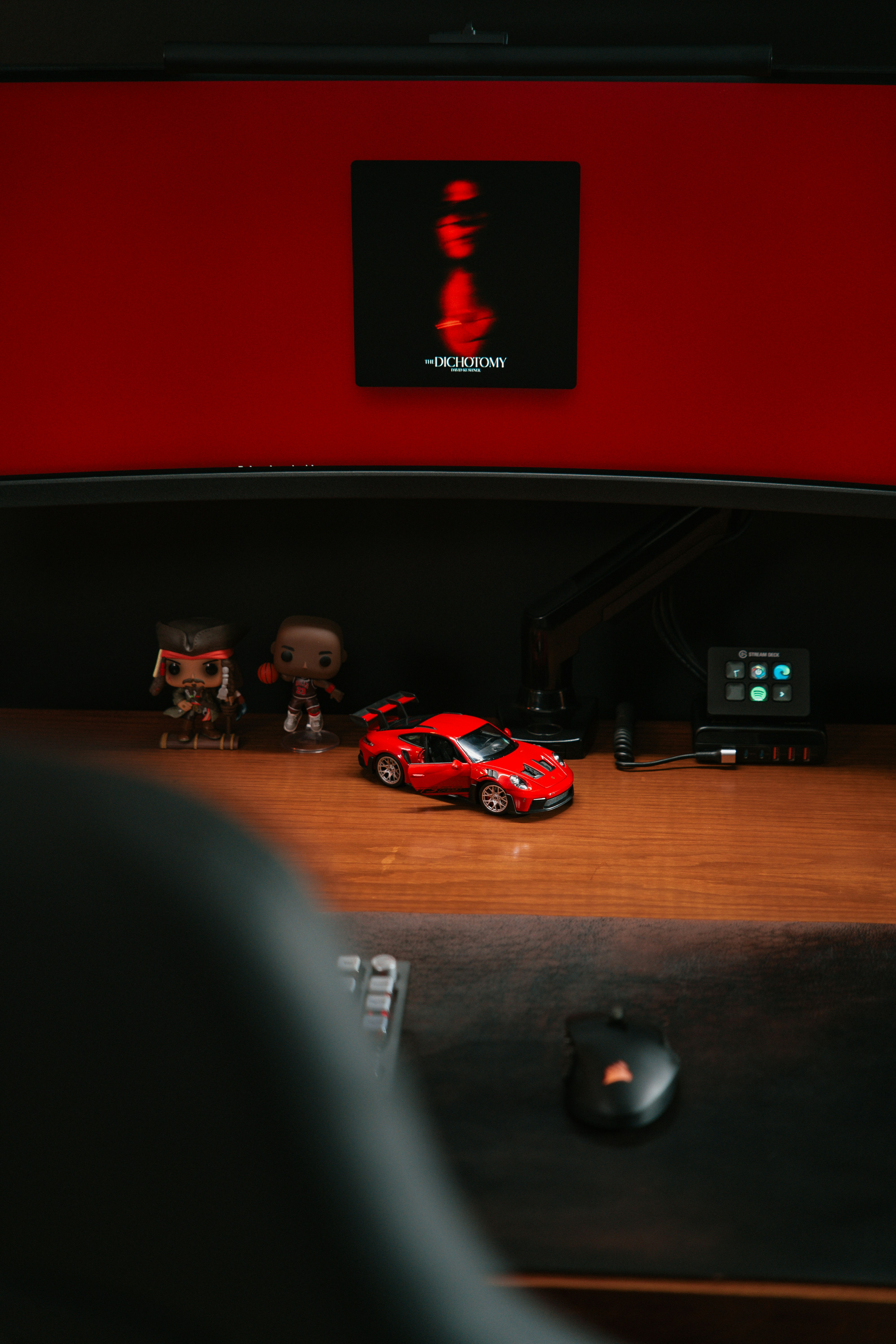 Coche de juguete rojo sobre un escritorio de madera con figuras.