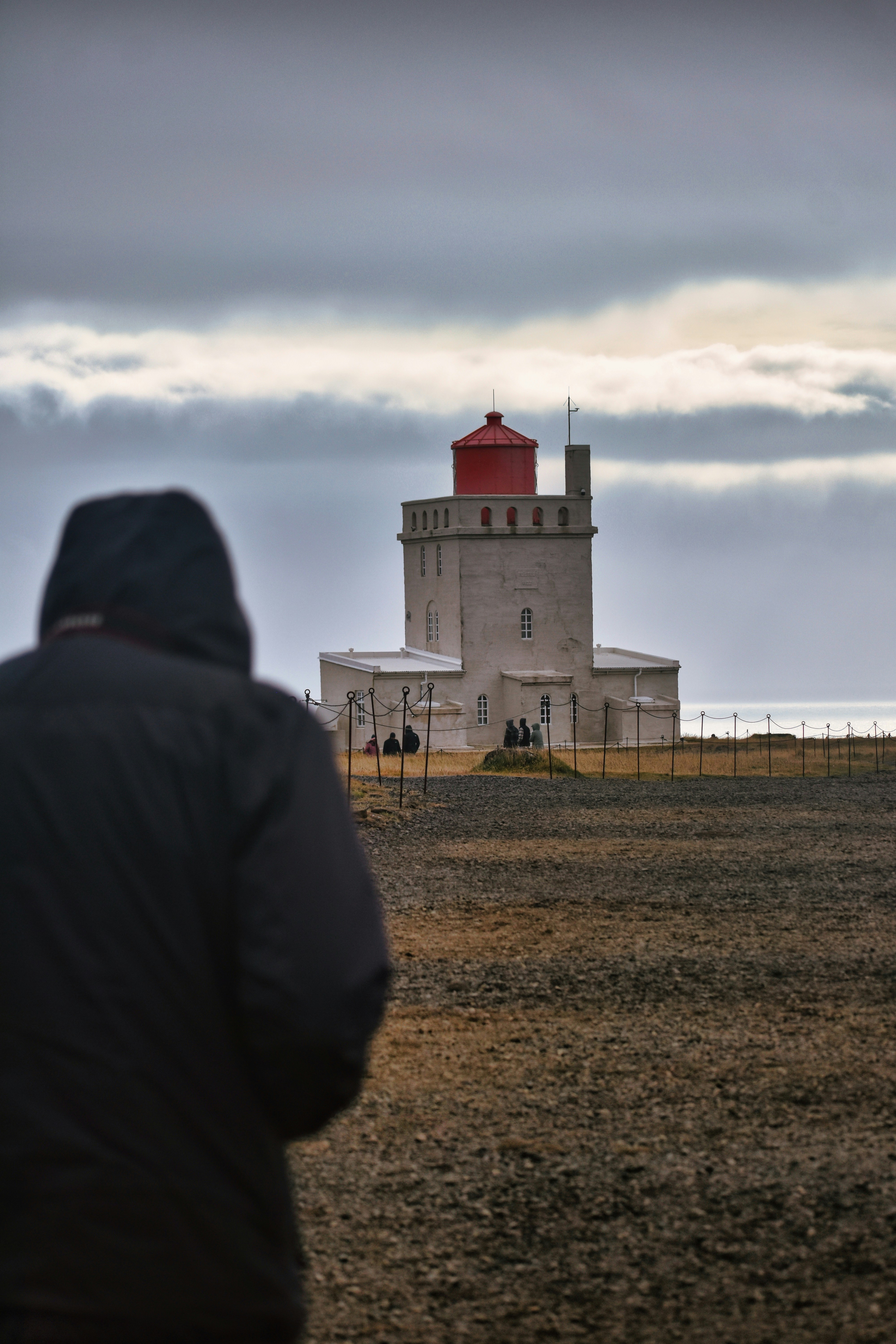 Person im Vordergrund betrachtet den Leuchtturm an bewölktem Tag