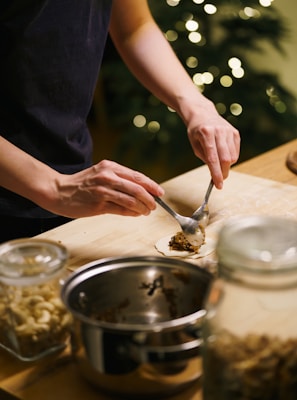 Hands filling small dough circles with filling.