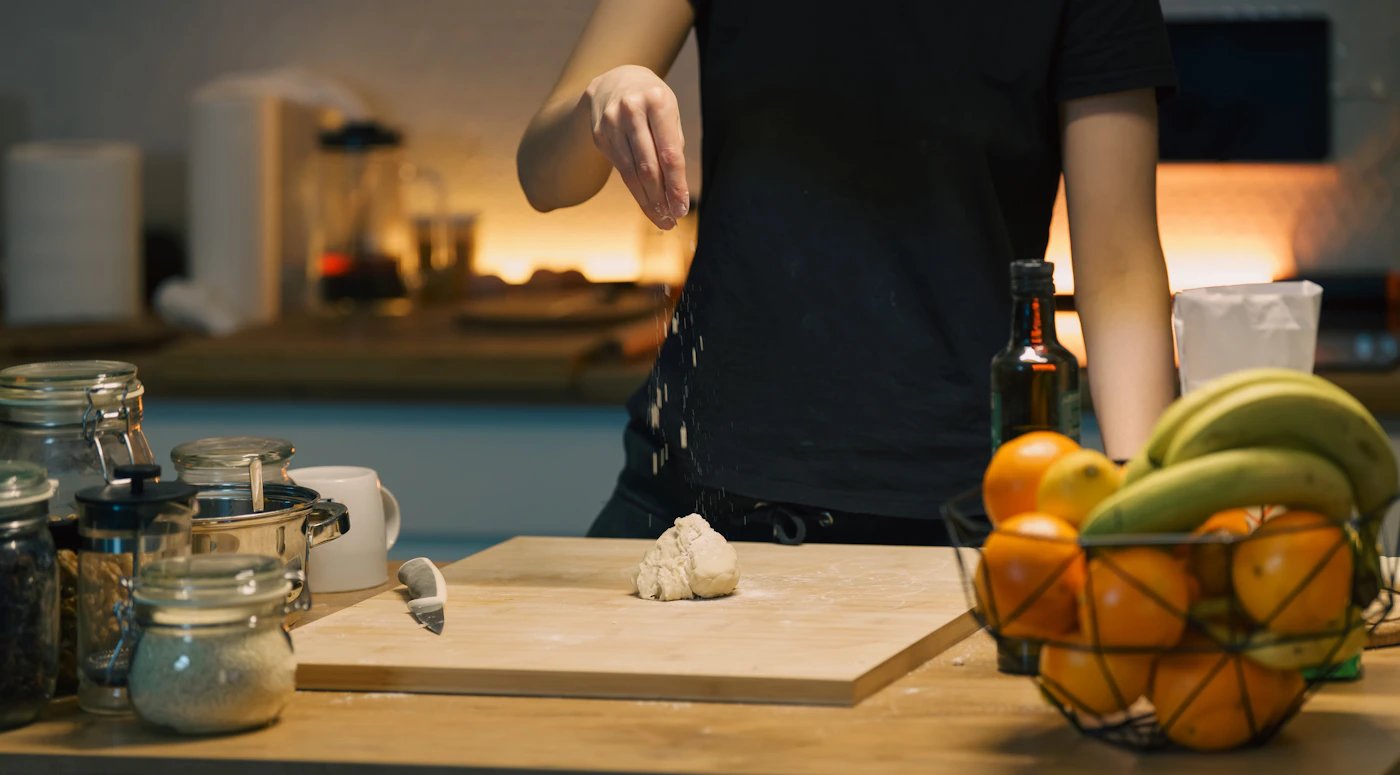 Dough being prepared on a wooden board in a home kitchen