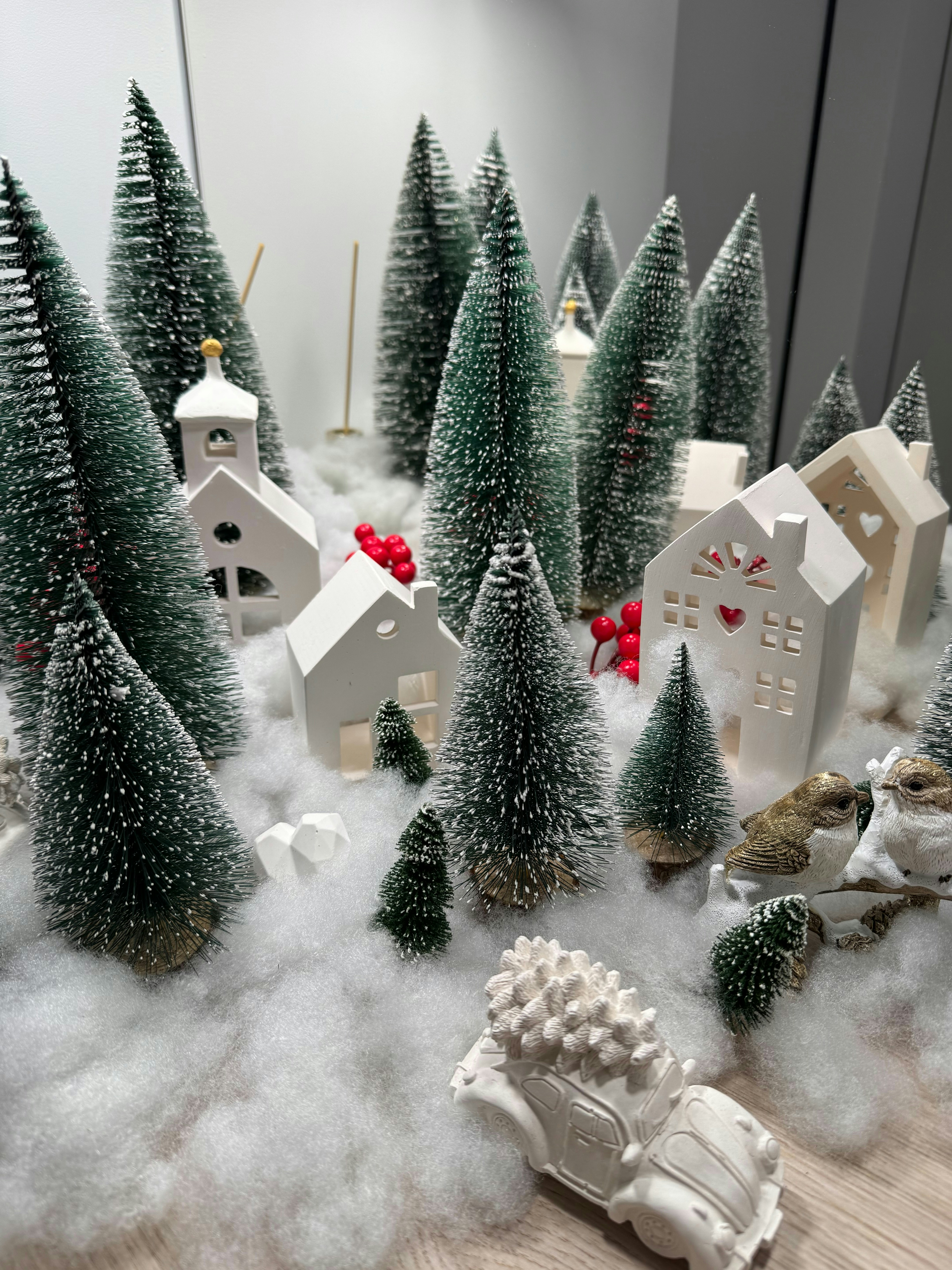 Miniature christmas village with snow-covered trees and houses.