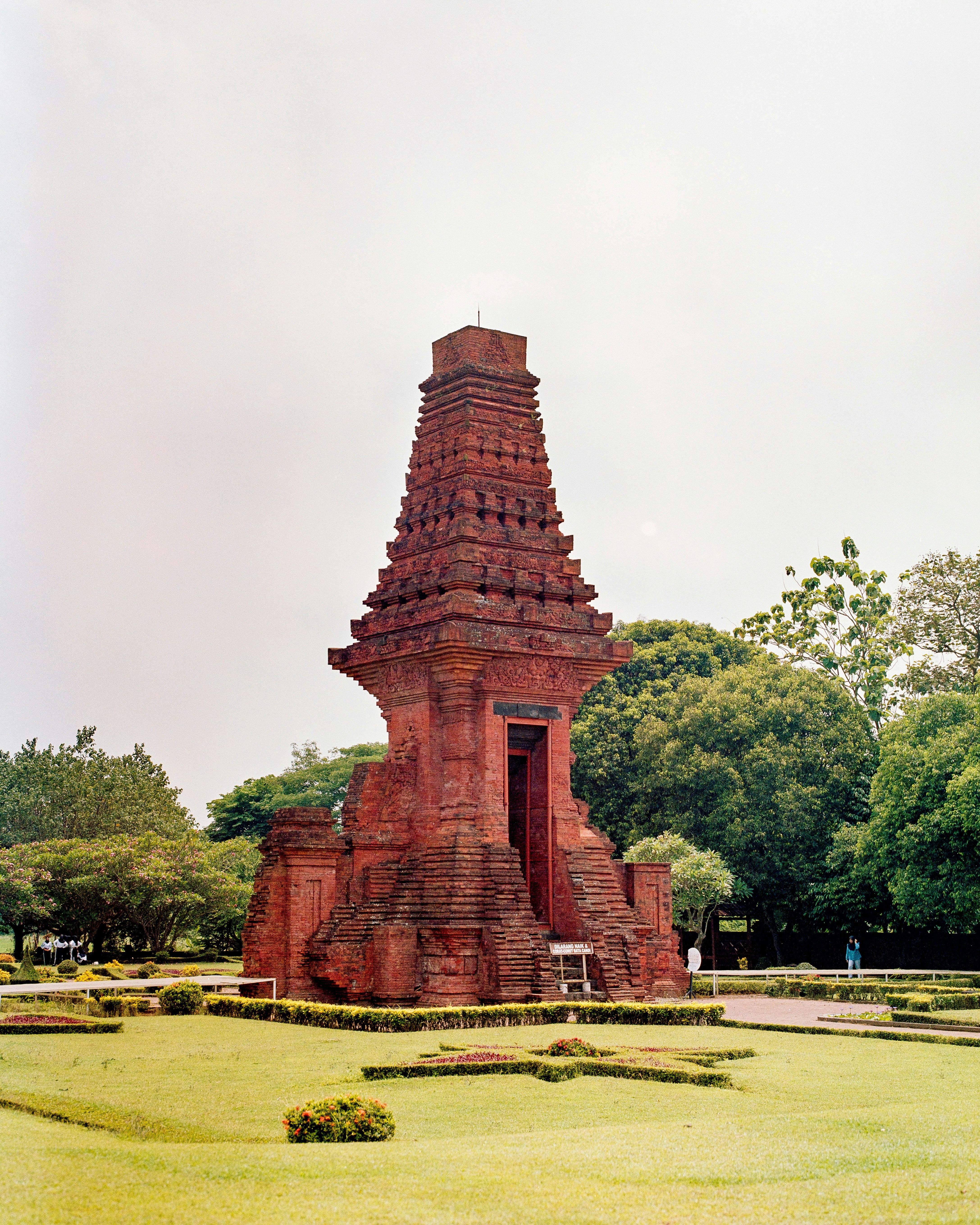 Struktur candi bata kuno dikelilingi oleh pepohonan hijau.