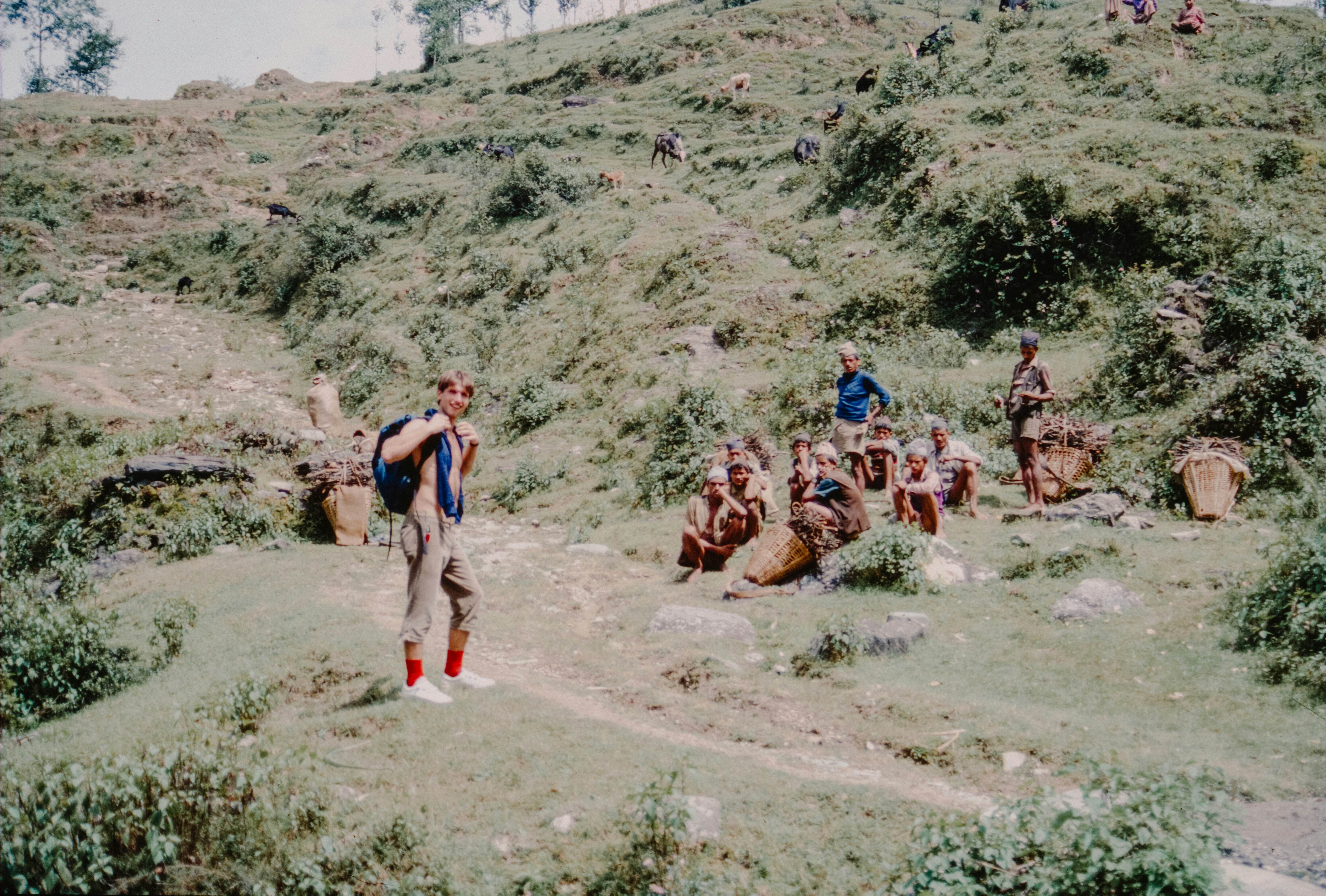 A tense scene of villagers confronting police officers in a rural setting, with some commotion in the background.