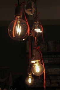 Several vintage edison bulbs hanging with red ribbons.