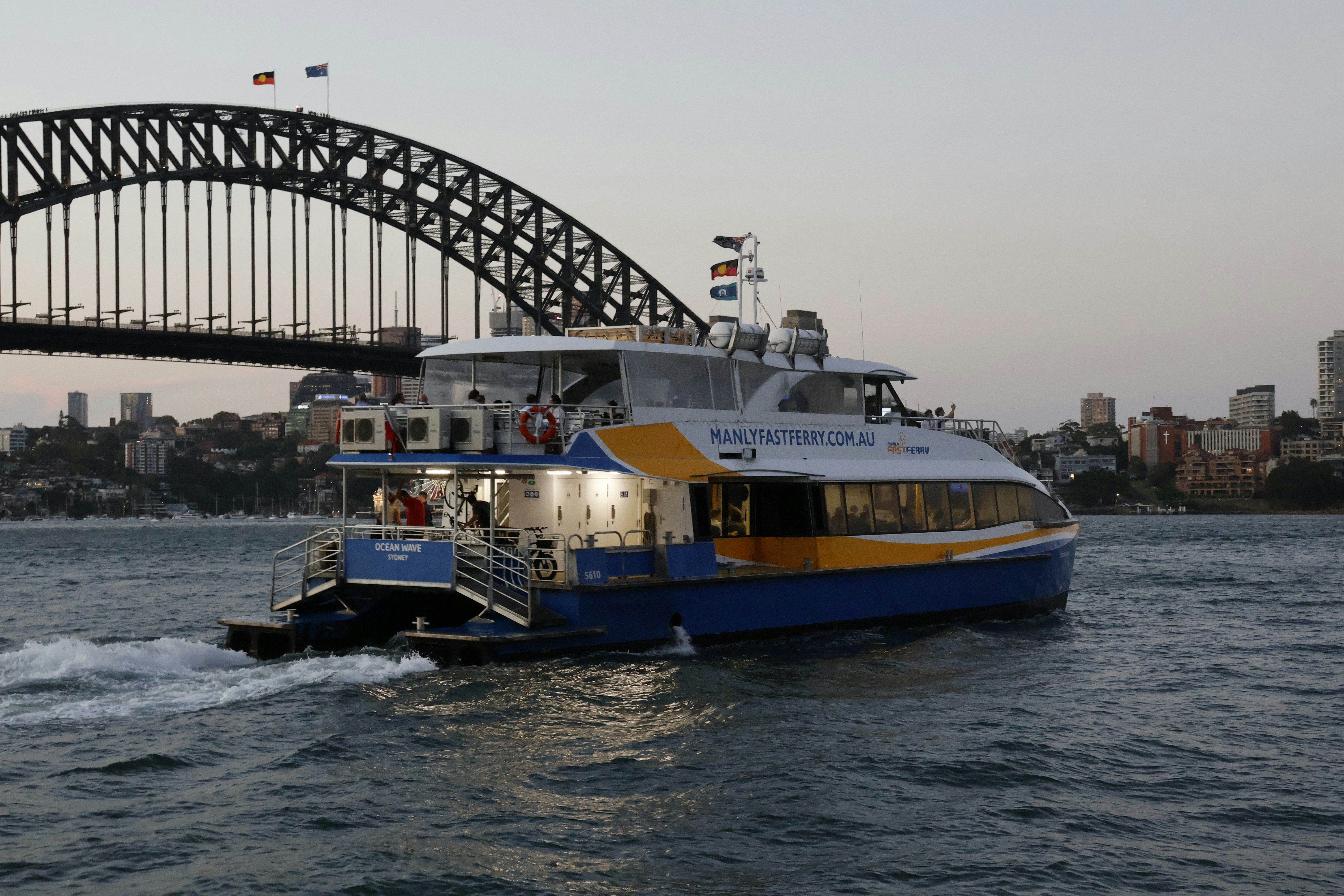 A Manly ferry passing the Sydney Harbour Bridge on the run to Circular Quay at dusk.