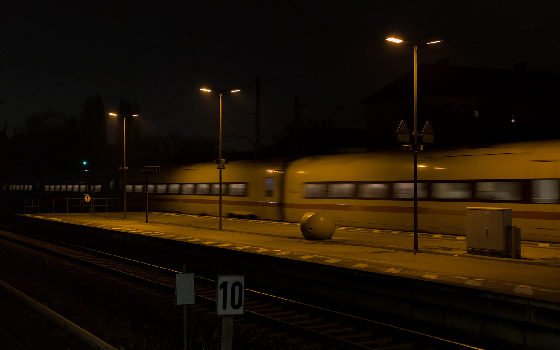 A train speeds through a station at night.