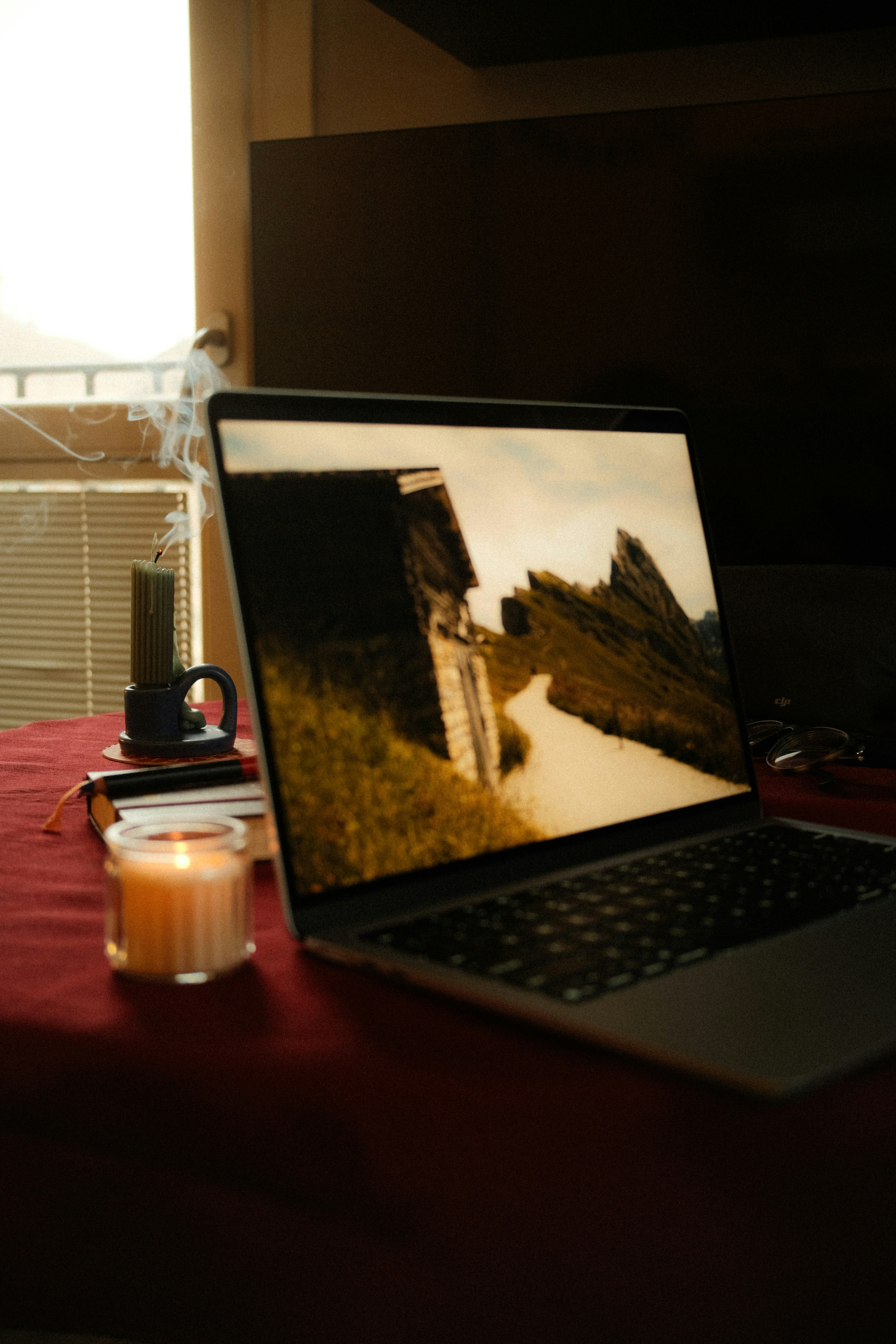 Laptop screen shows a rustic building and rocky landscape.
