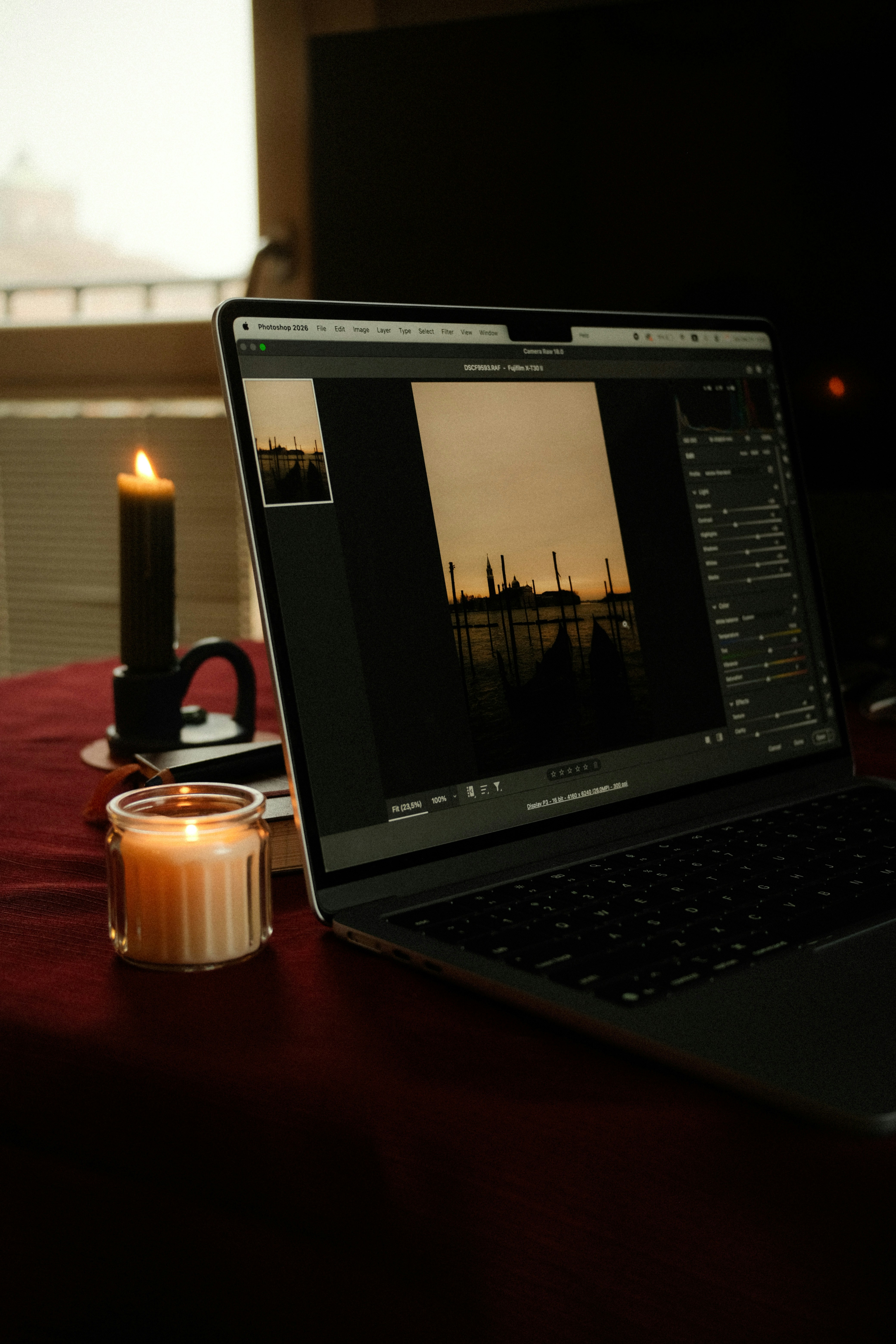 Laptop screen displays a cityscape next to lit candles.