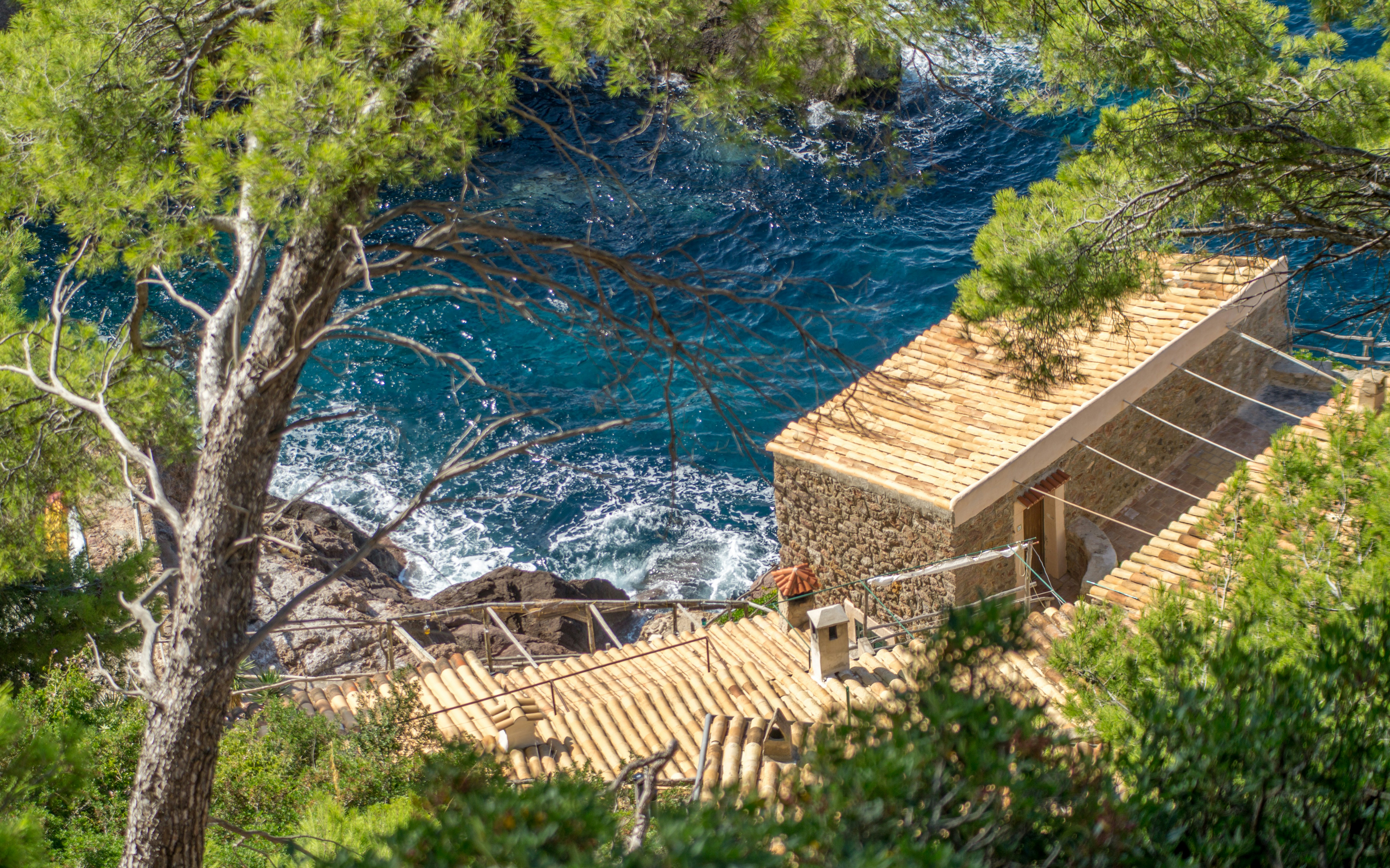 Stone house by the blue ocean with pine trees