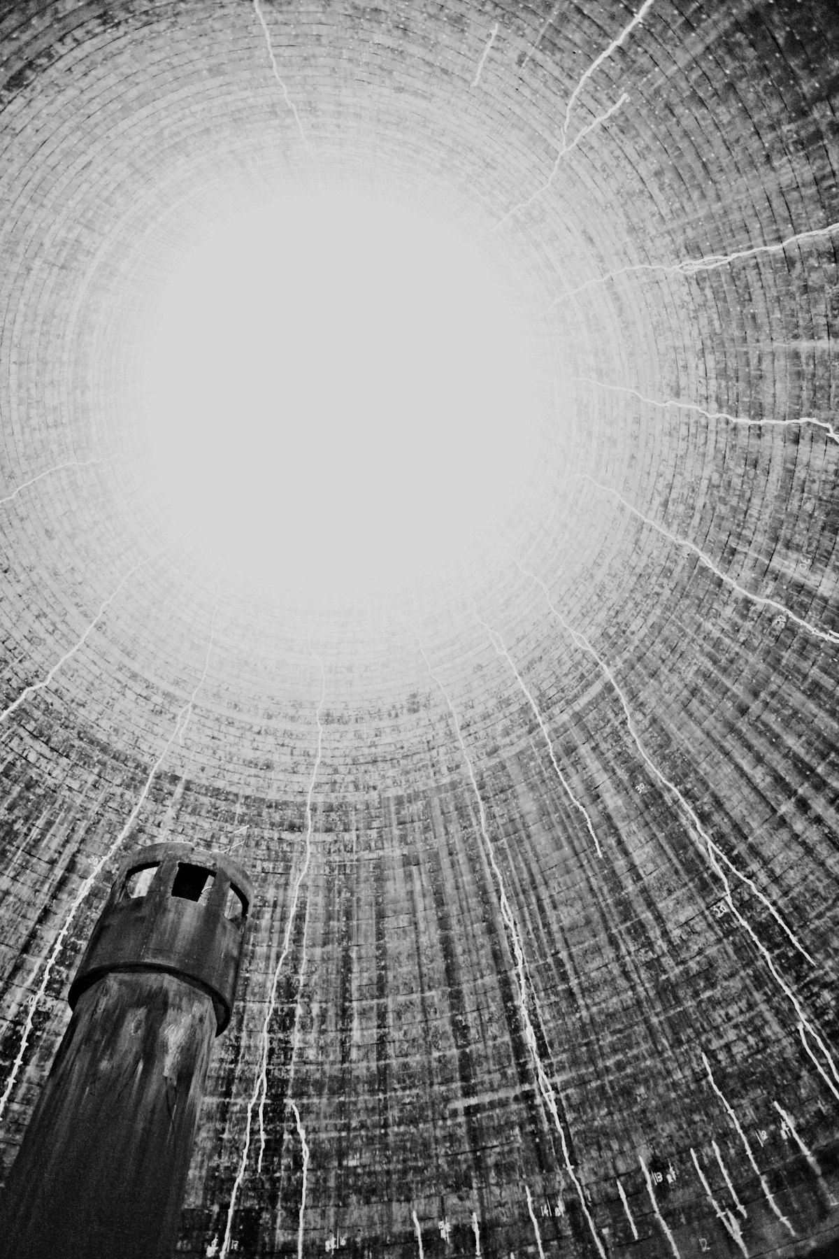 Looking upward inside the interior of a cooling tower showing the steel structure, internal piping, and central column — the scale and engineering of large field-erected cooling tower equipment. Photo: Phil Hearing / Unsplash