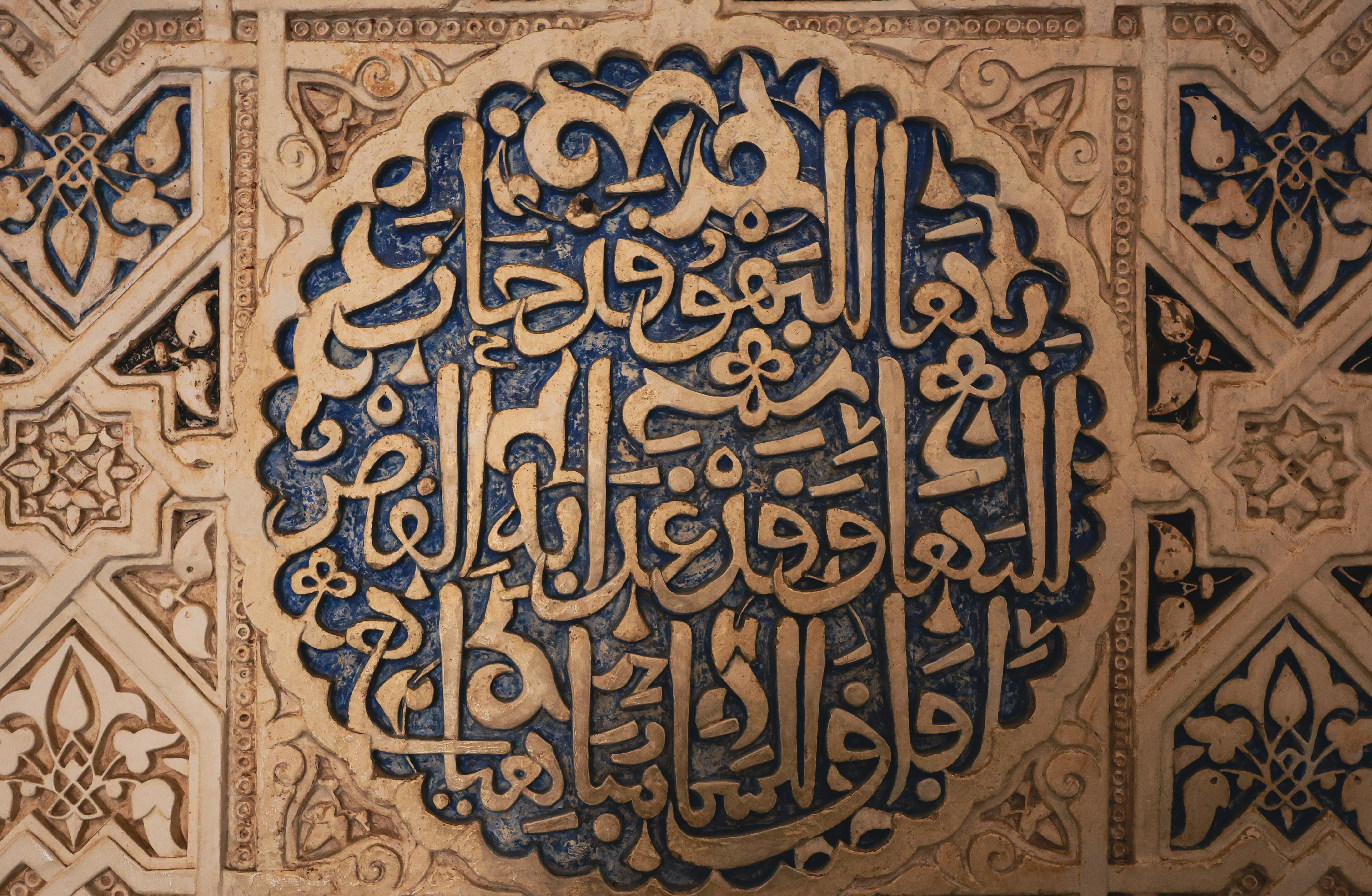 Intricate arabic calligraphy carved into a textured wall