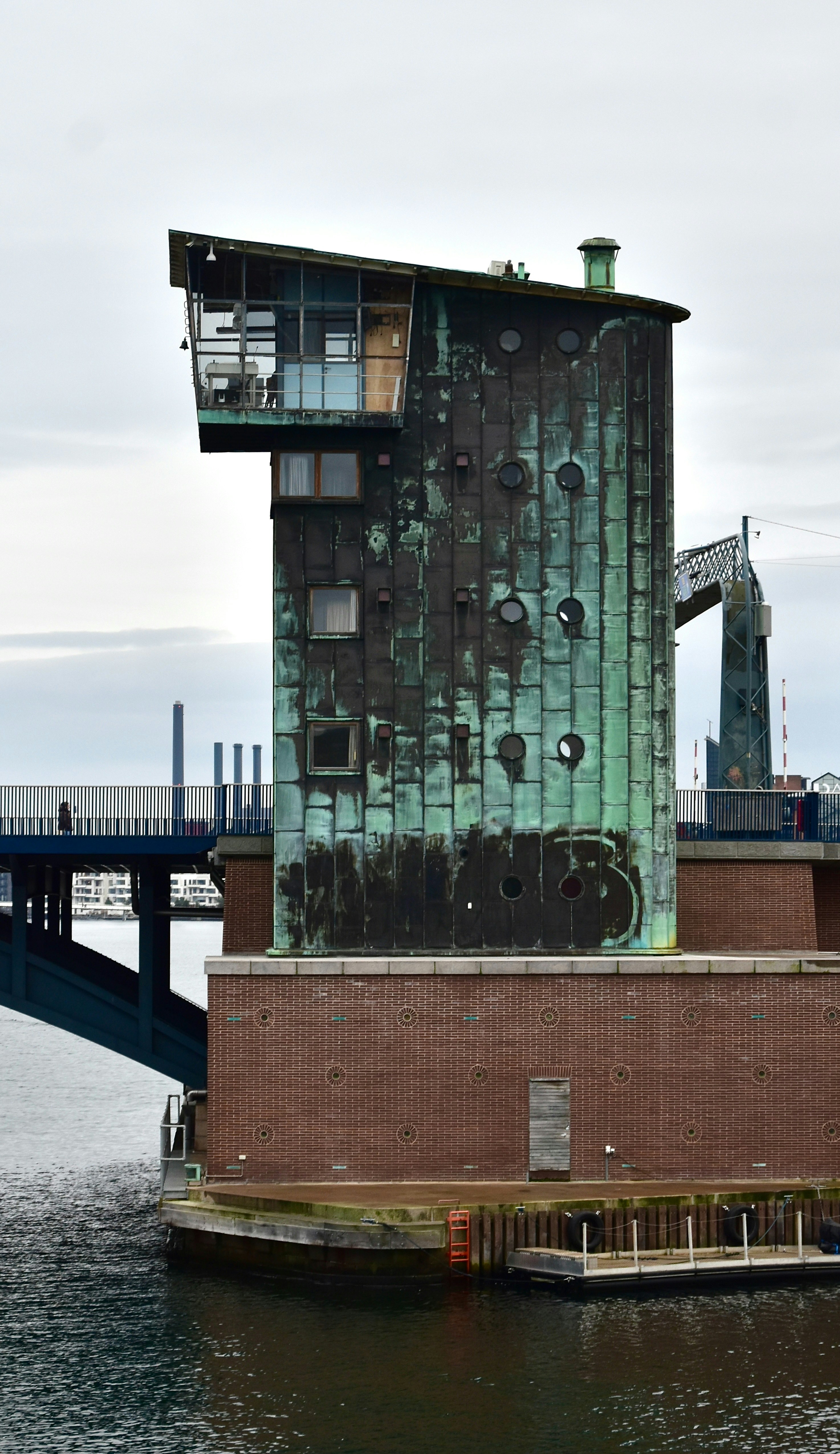 Verdigris tower beside a blue bridge and water