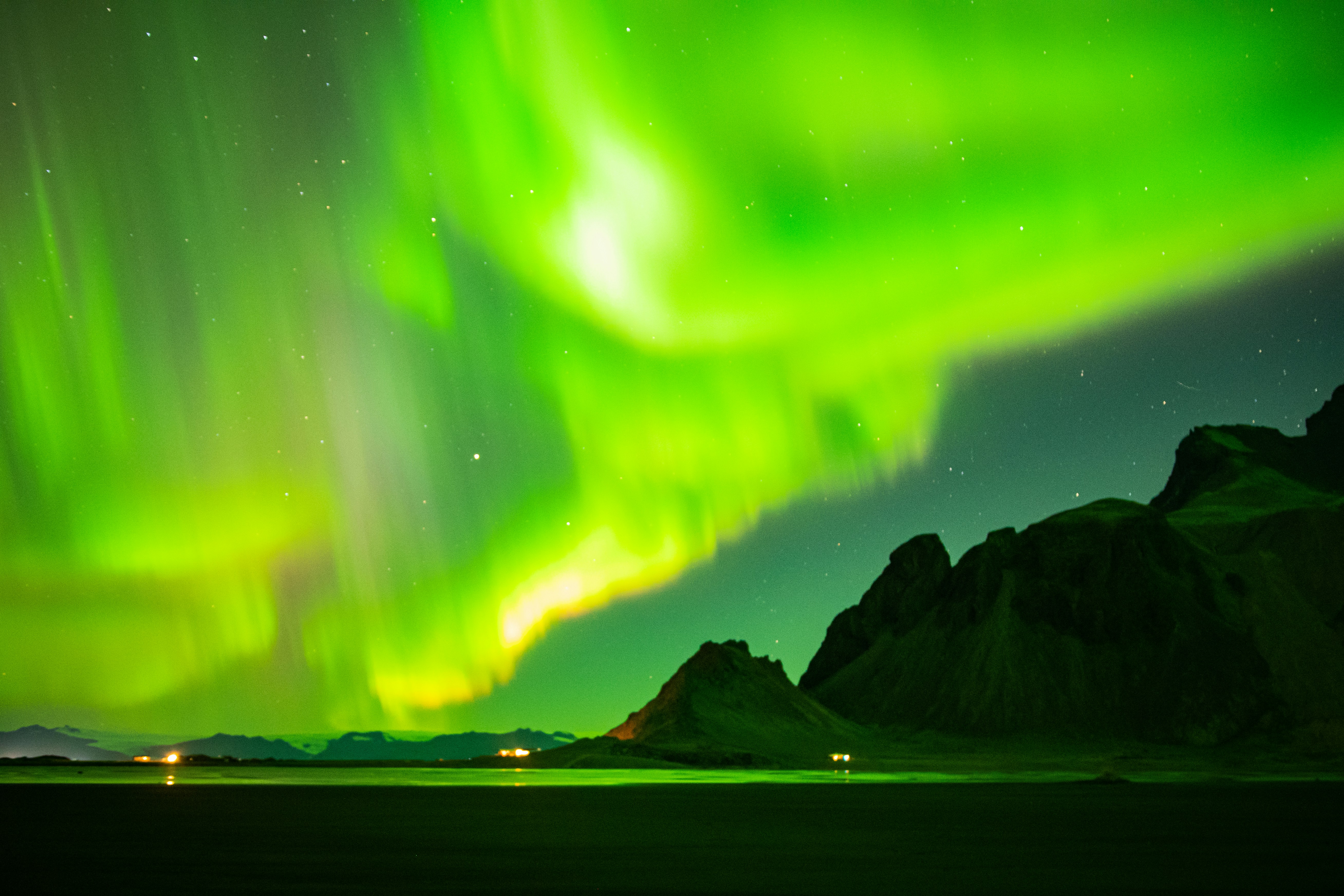 Vibrant green aurora borealis over dark mountains