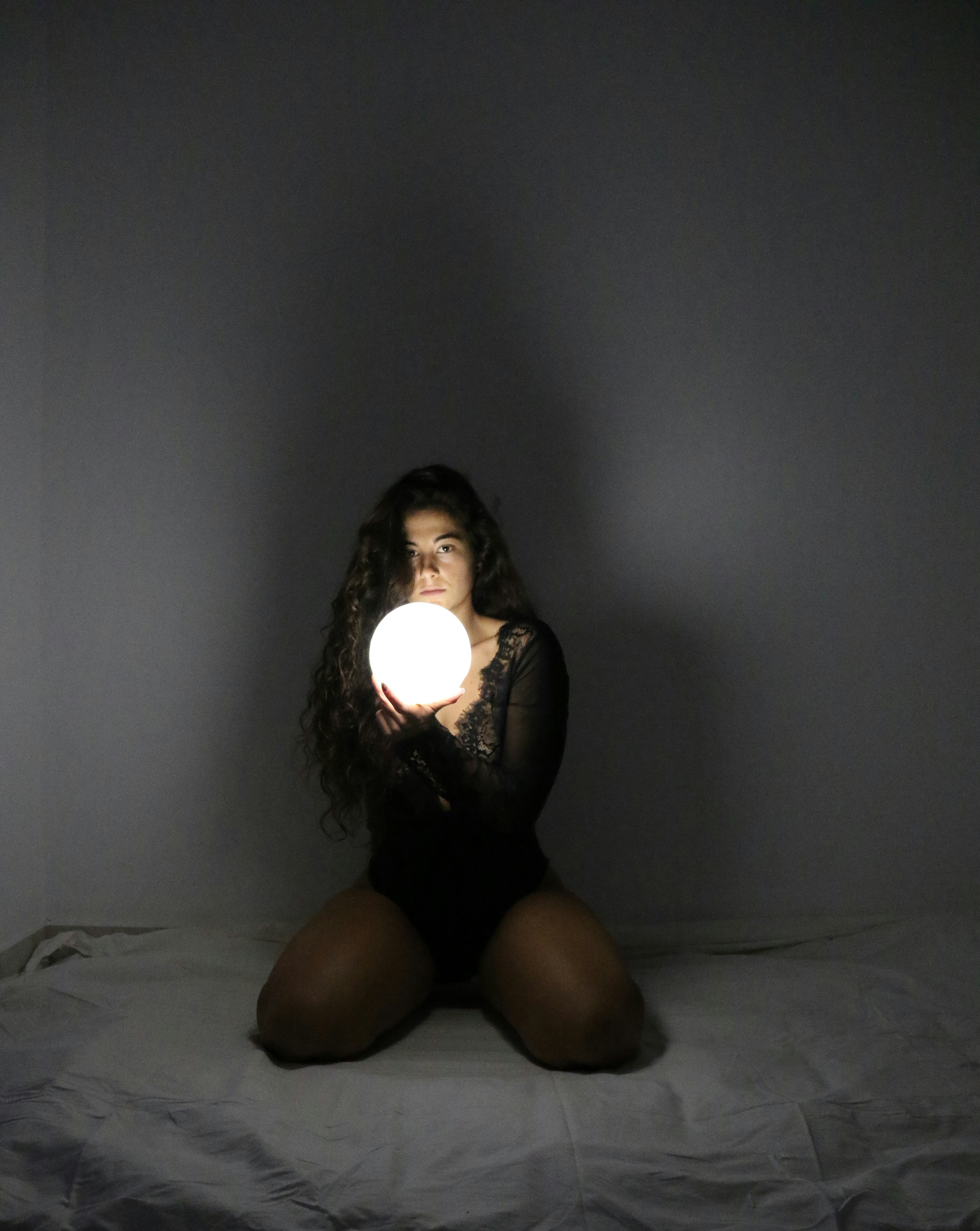 Woman holding a glowing orb on her lap.