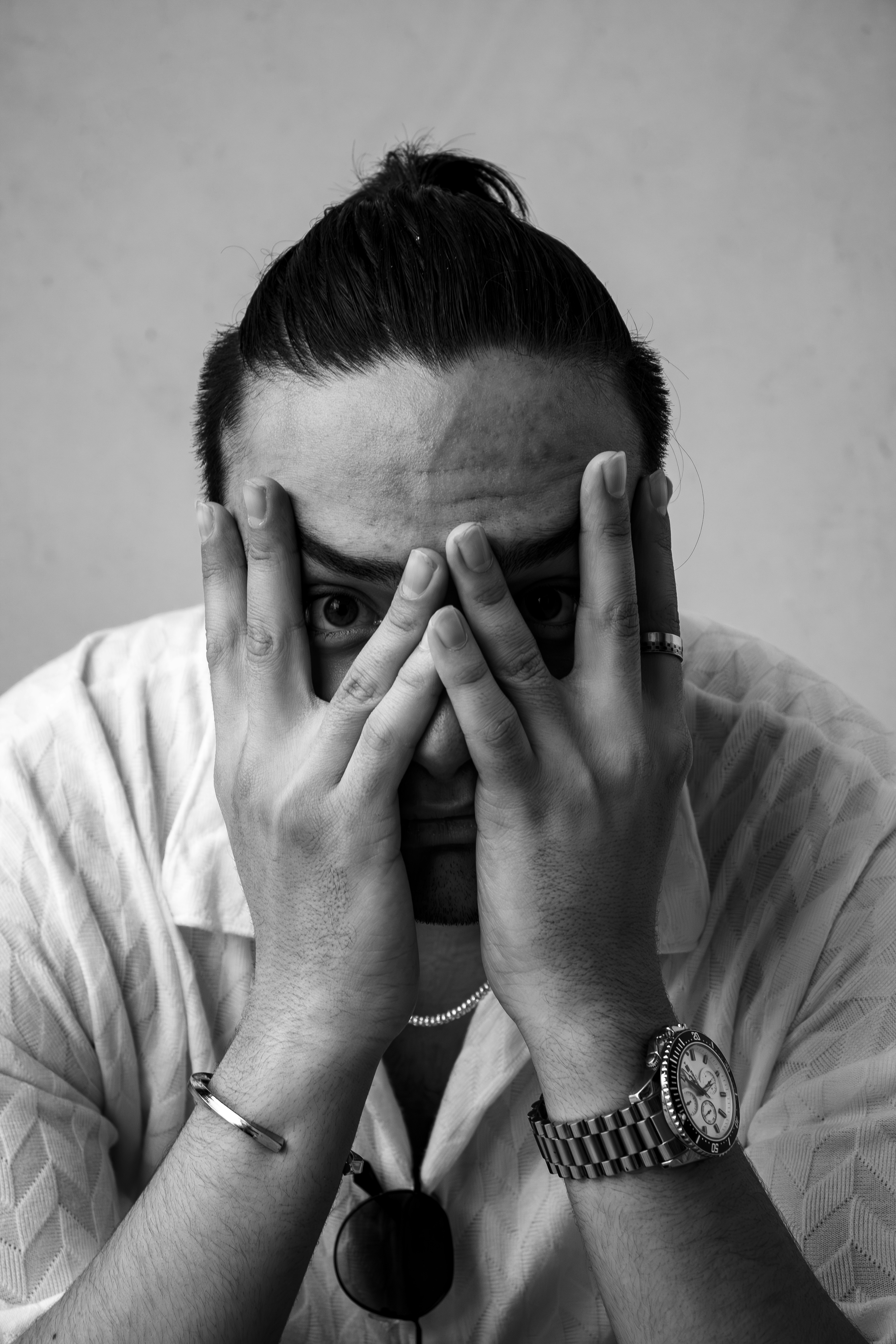 Mann bedeckt das Gesicht mit den Händen und schaut durch die Finger.