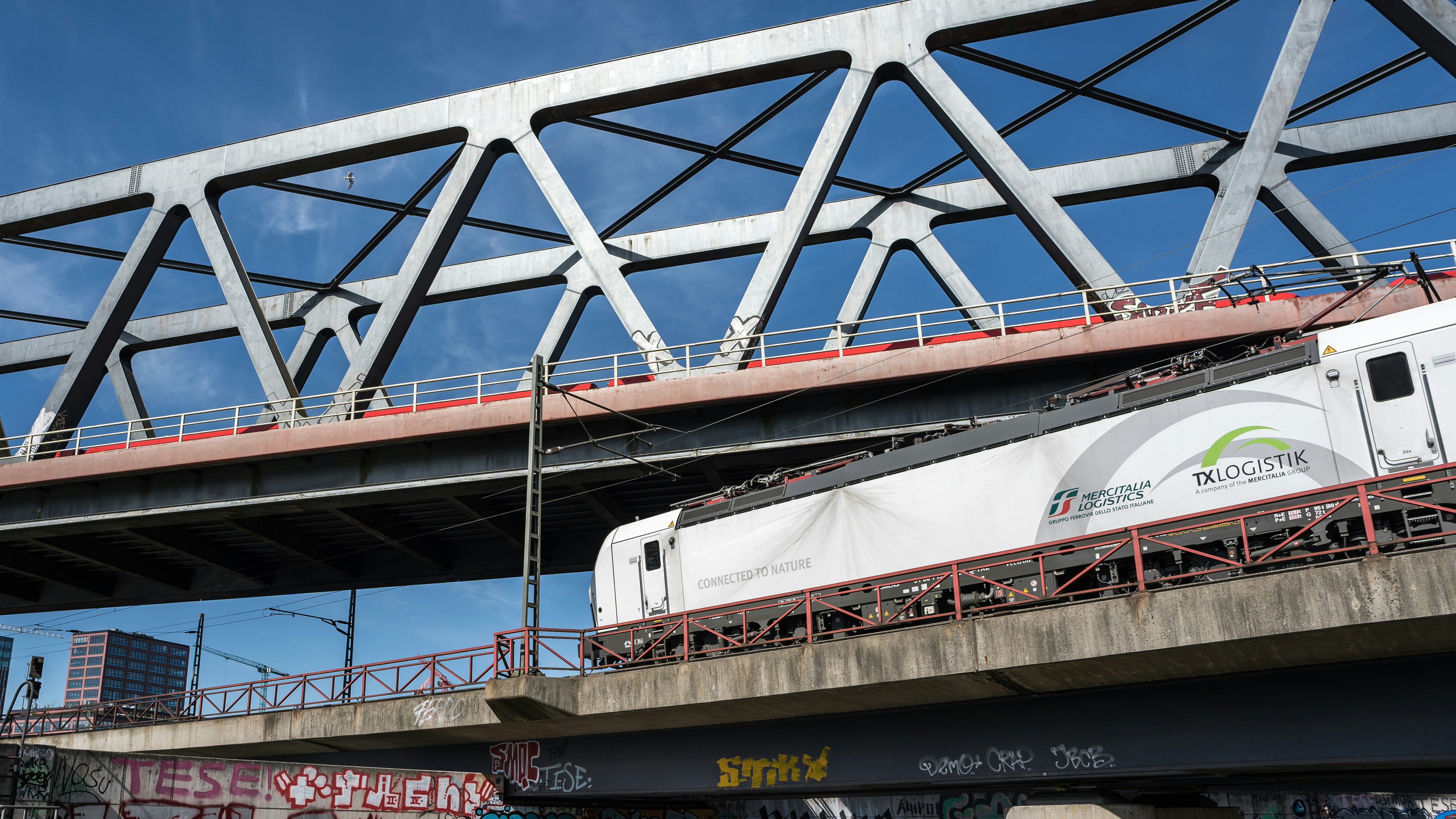 Train crossing a bridge under a larger bridge.