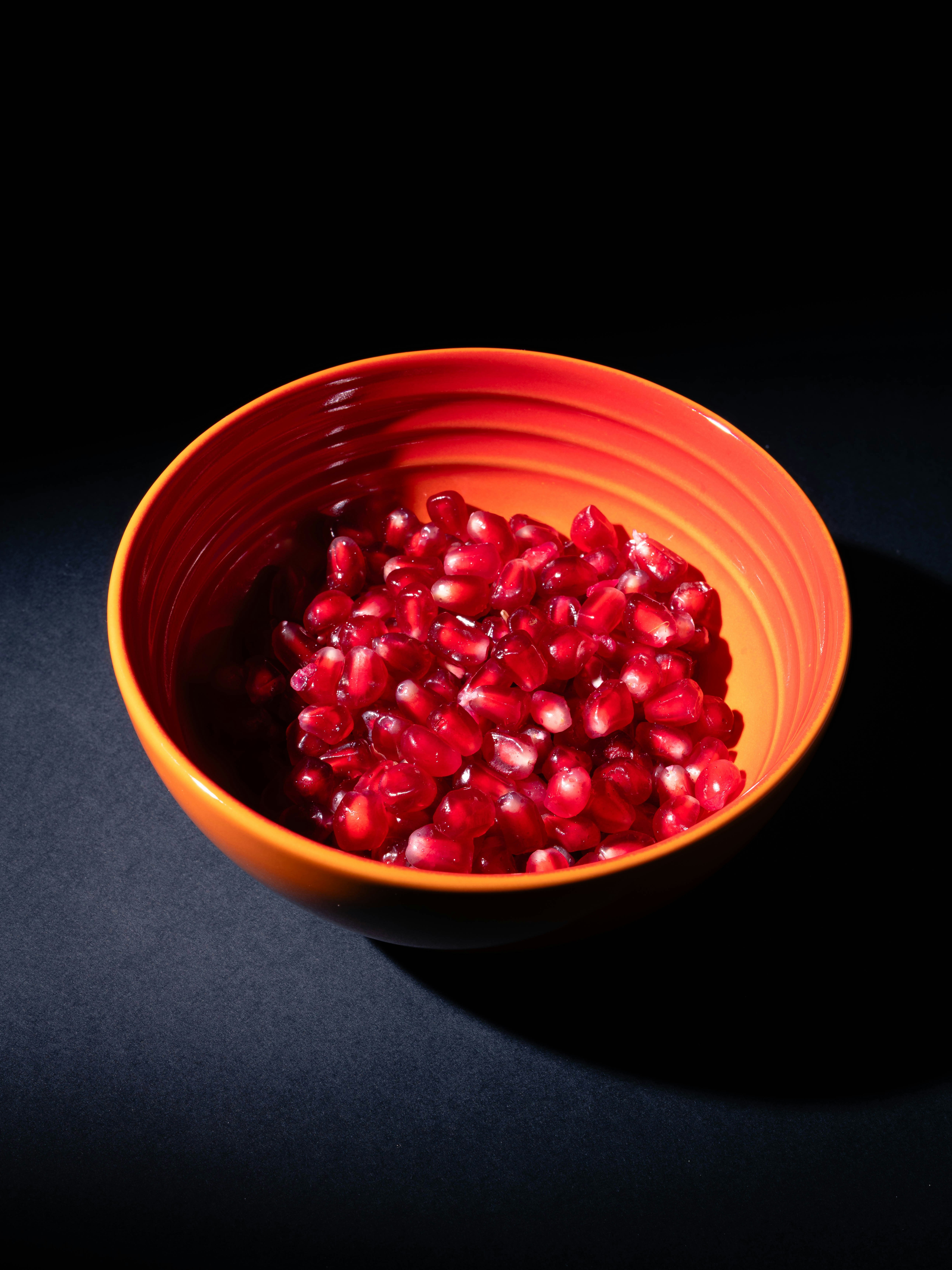 Bowl of fresh pomegranate seeds on dark background