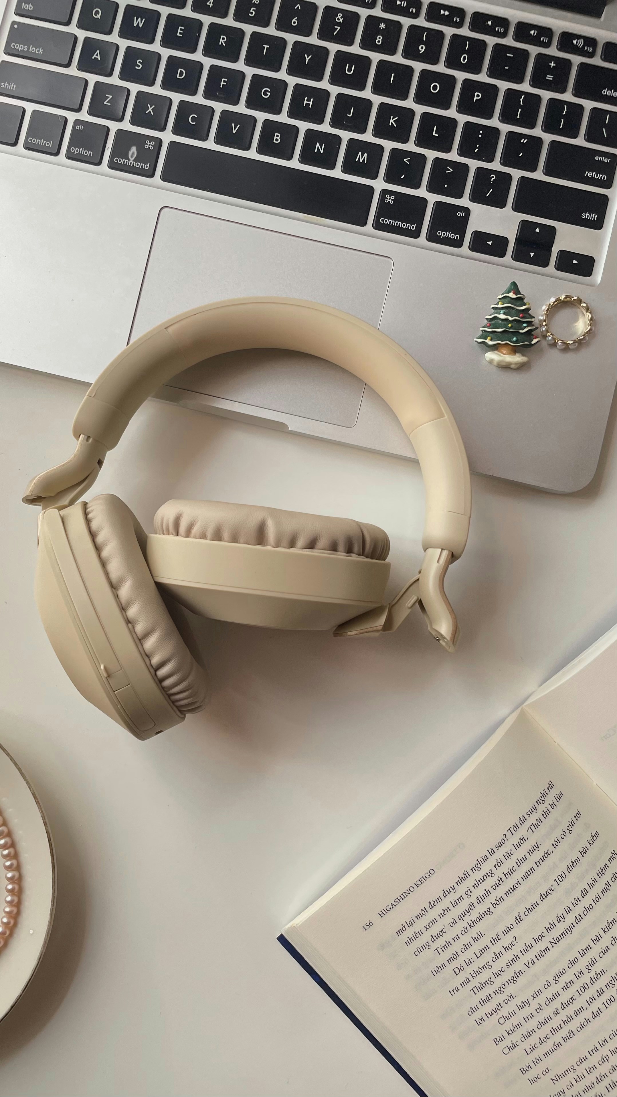 Headphones rest on a laptop next to an open book.