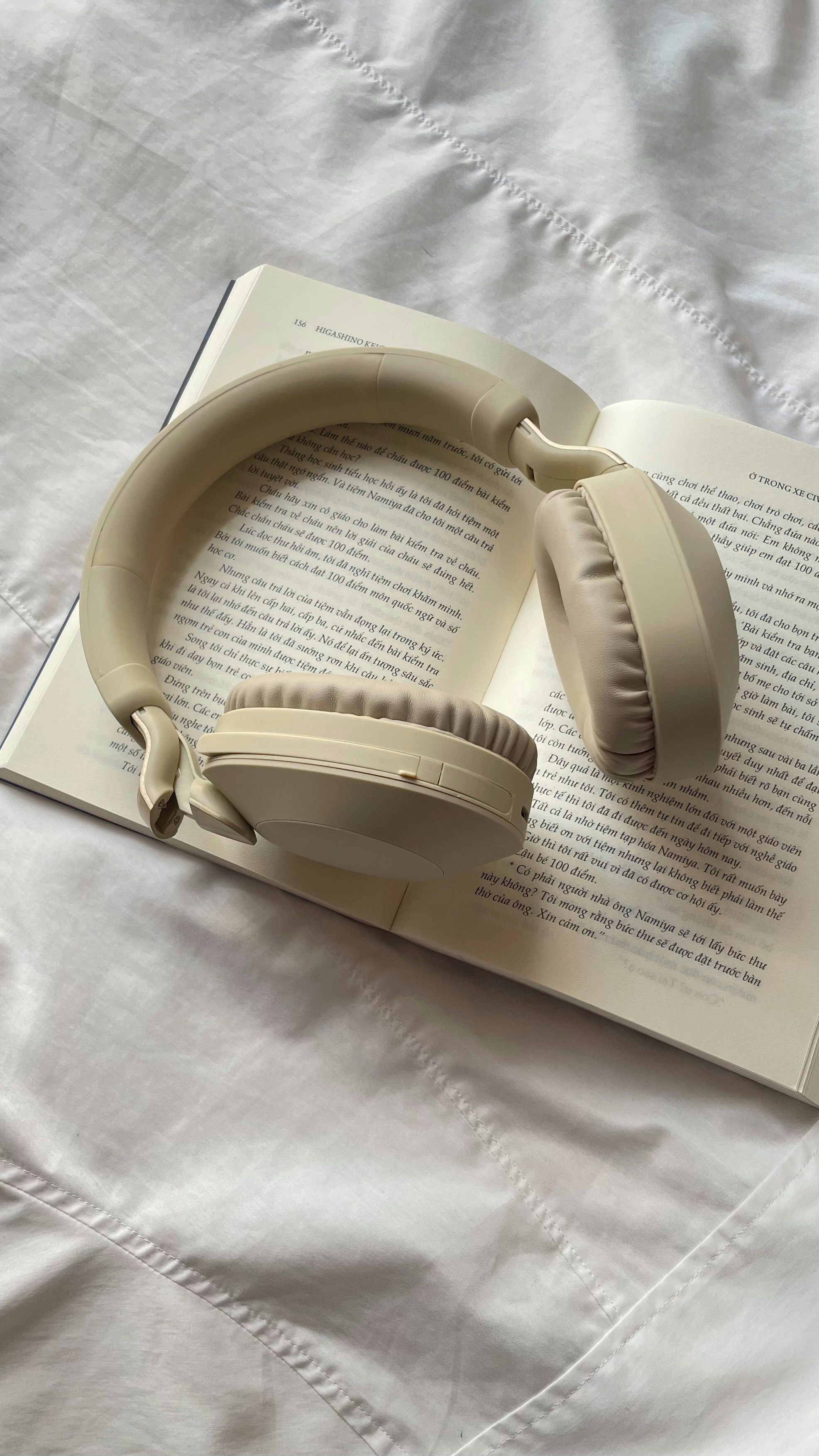Cream colored headphones resting on an open book.