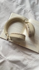 Cream colored headphones resting on an open book.