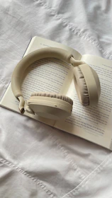 Cream colored headphones resting on an open book