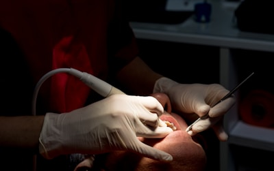 Dentist cleaning patient's teeth with tools.