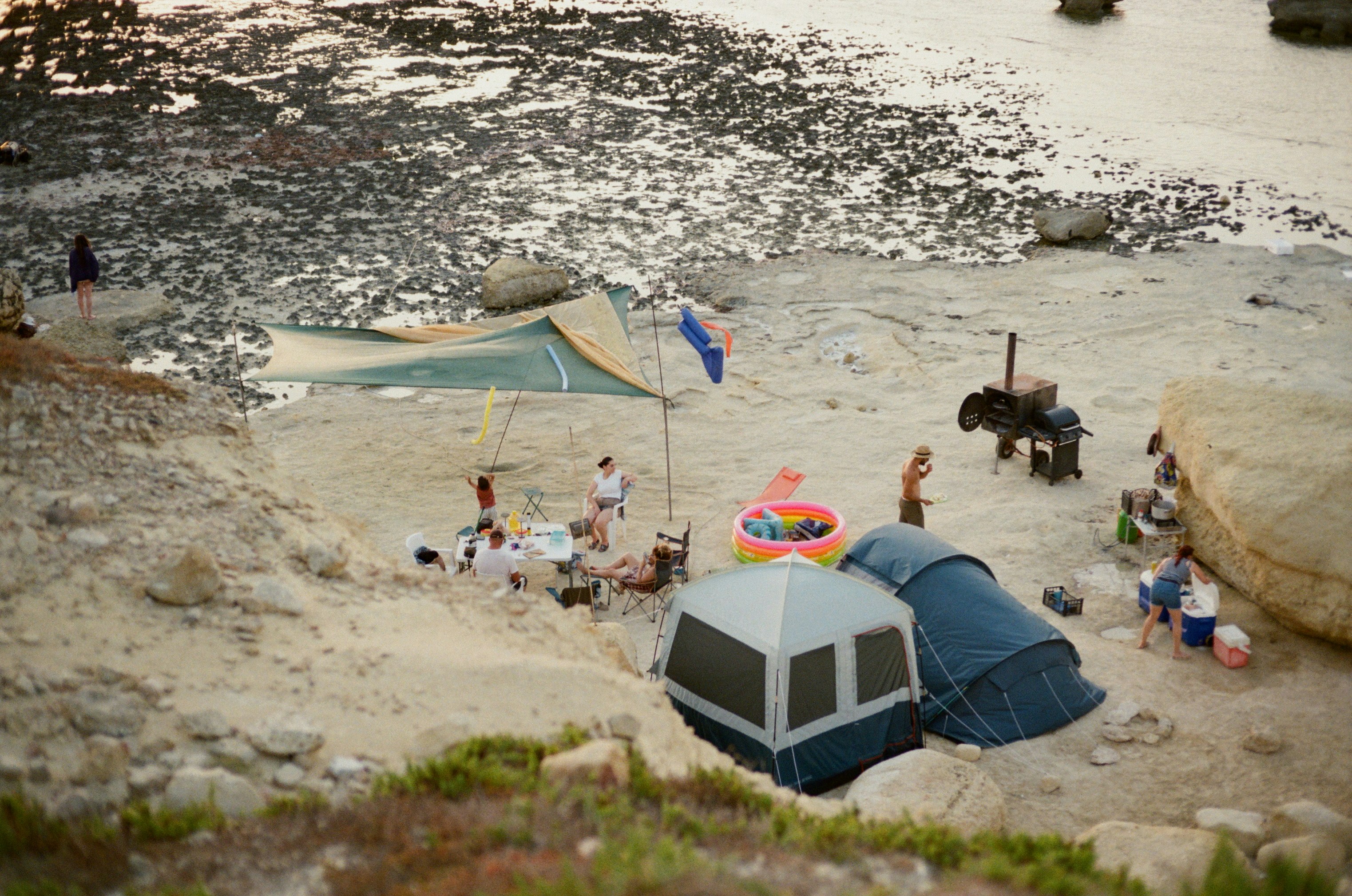 People camping on a rocky beach near the ocean.