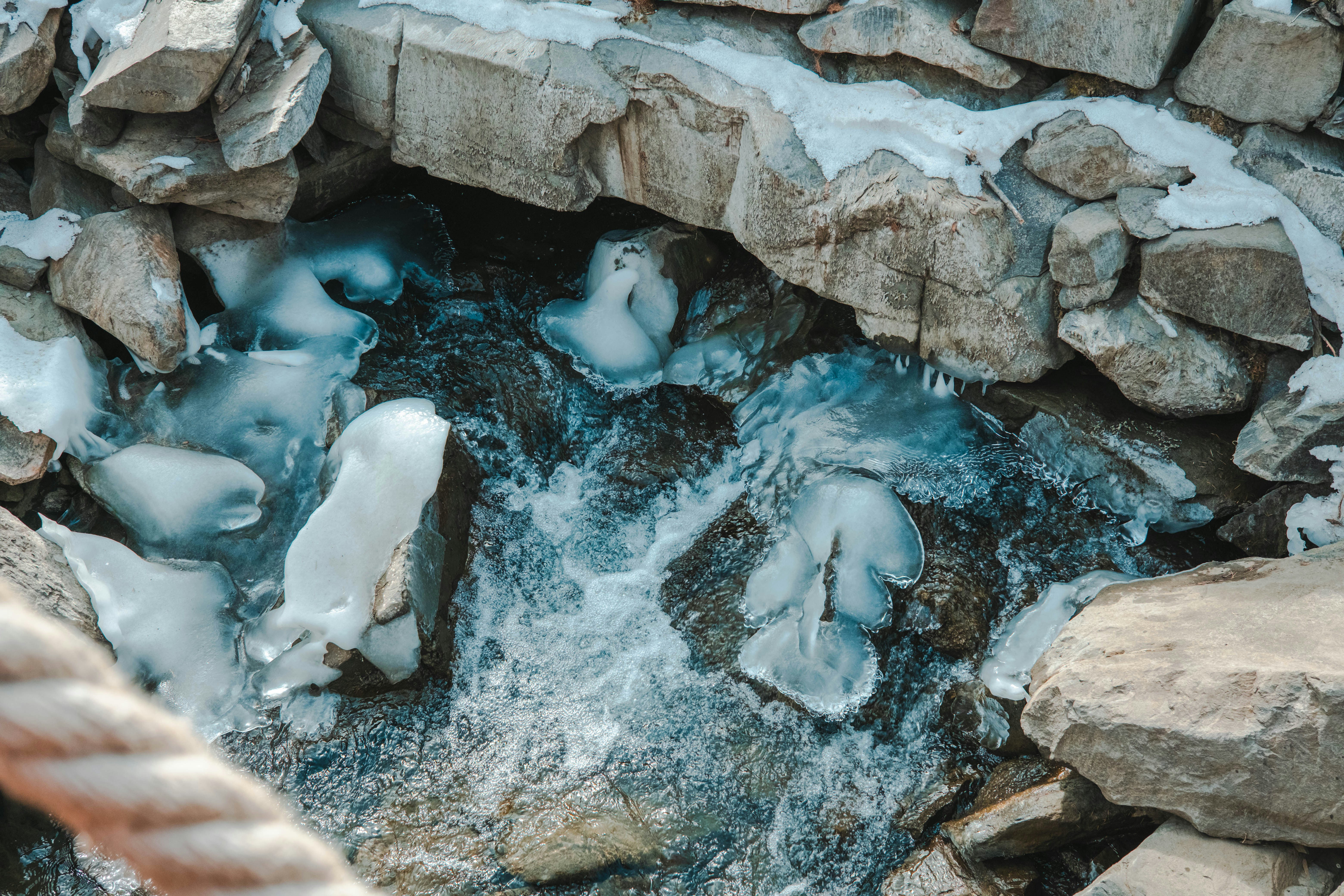 Arroyo congelado que fluye sobre rocas en invierno