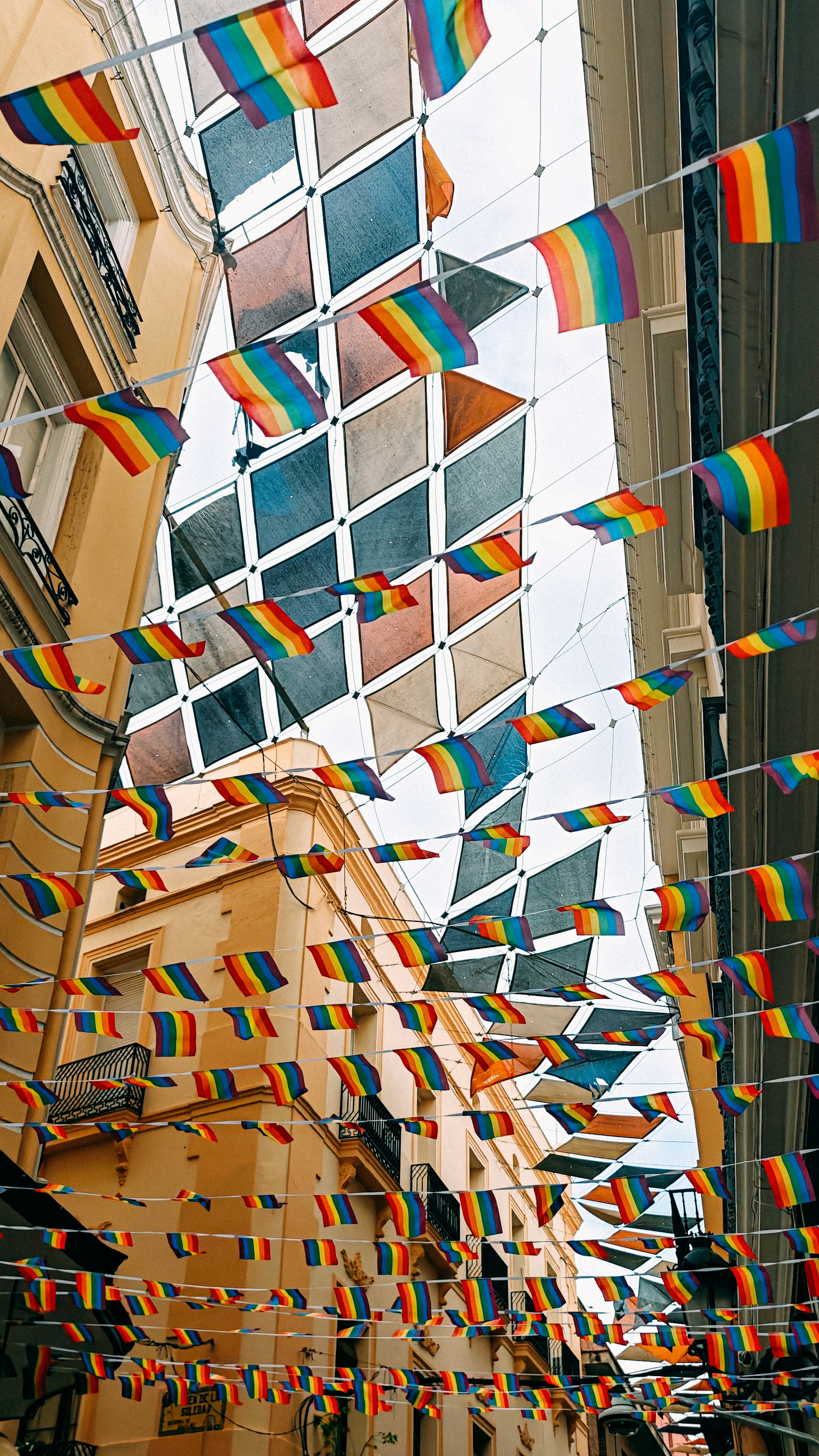 Rainbow flags strung across a city street.