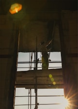 Construction worker on scaffolding at sunset.