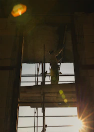 Construction worker on scaffolding at sunset.