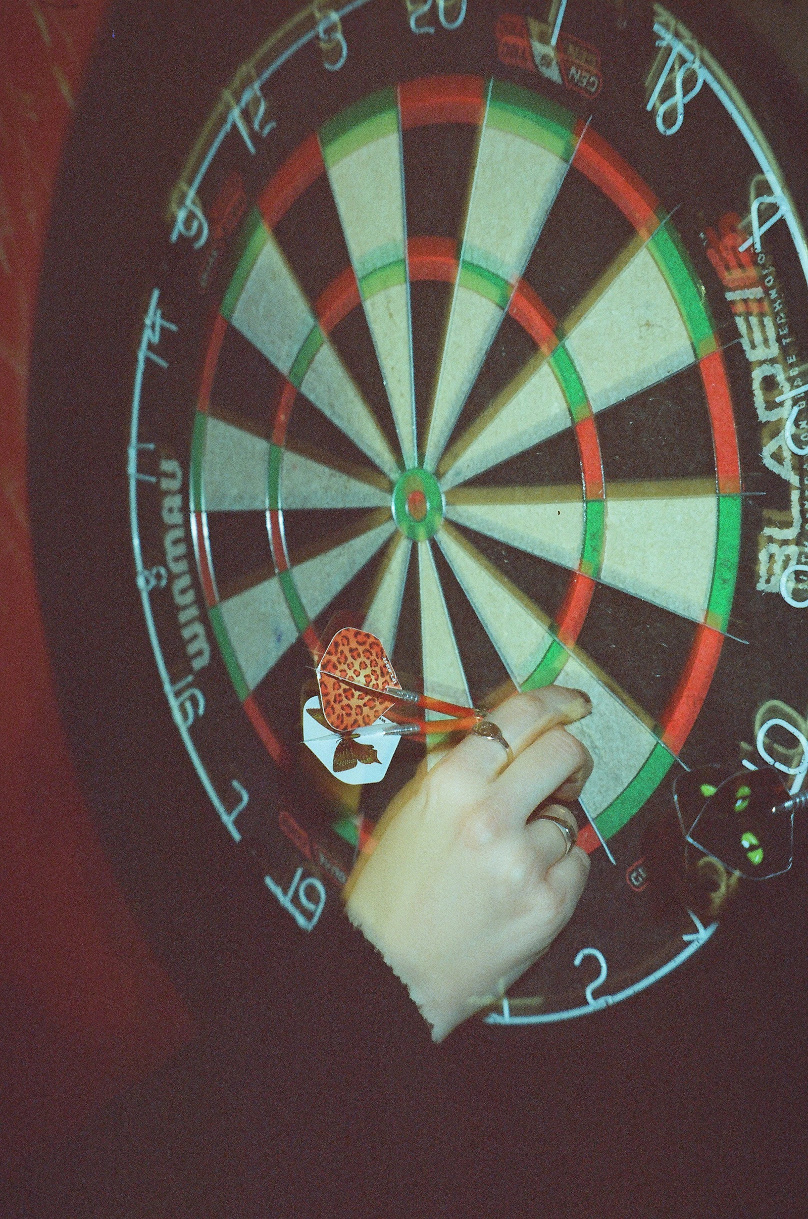 Symbolfoto: Hand setzt einen Dartpfeil in eine Dartscheibe