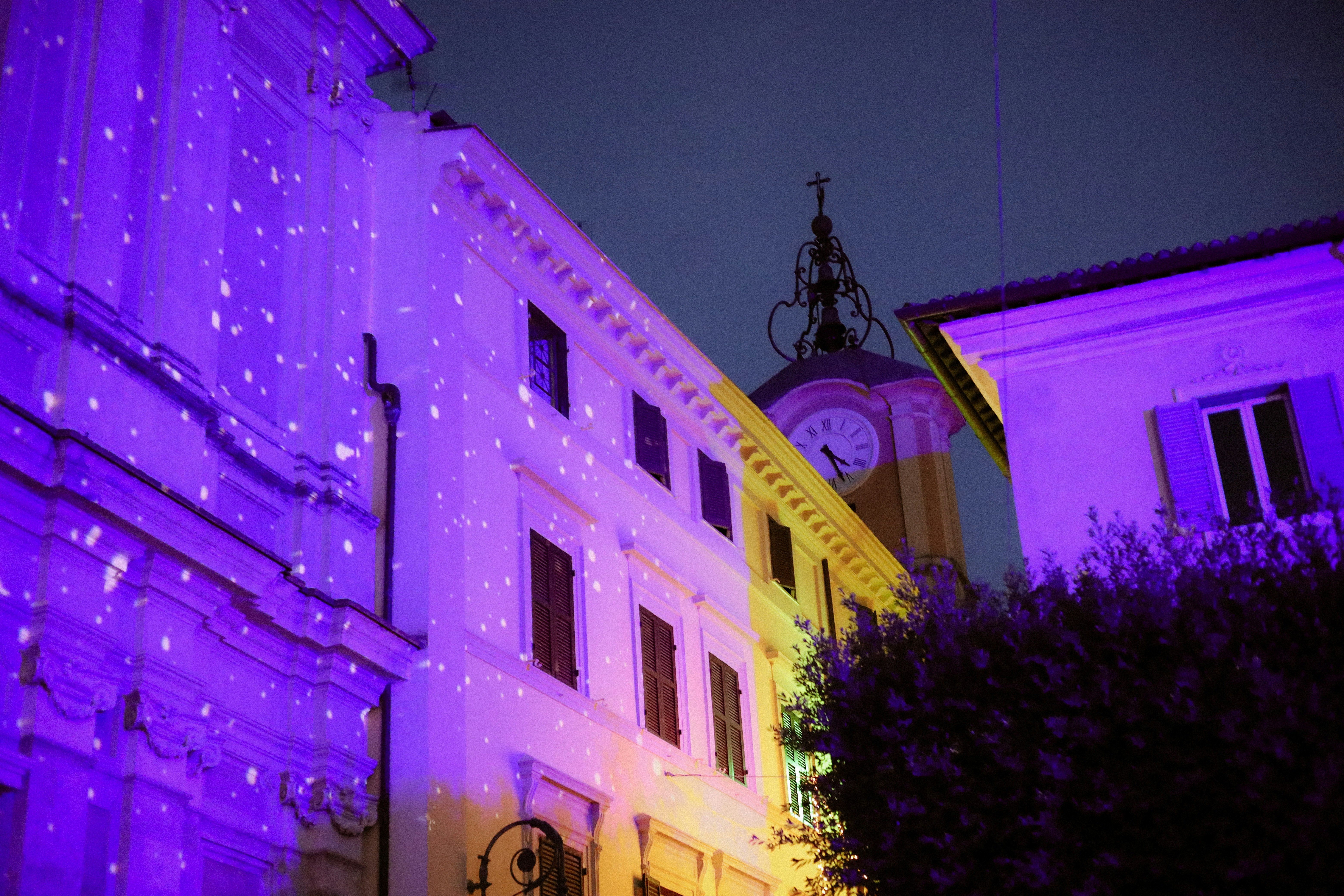 Buildings illuminated with purple and yellow lights at night.