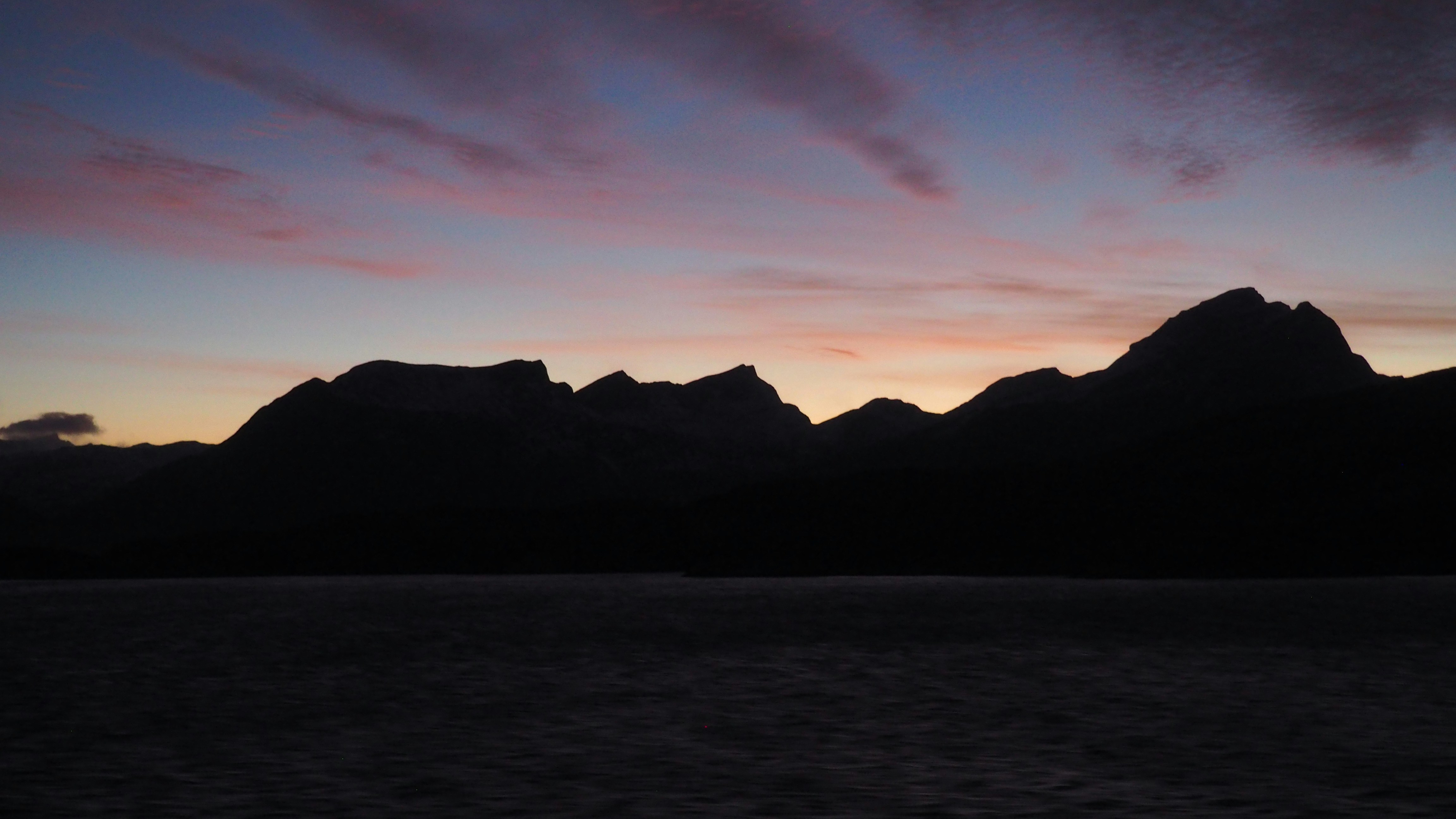 Silhouette of mountains against a colorful twilight sky.