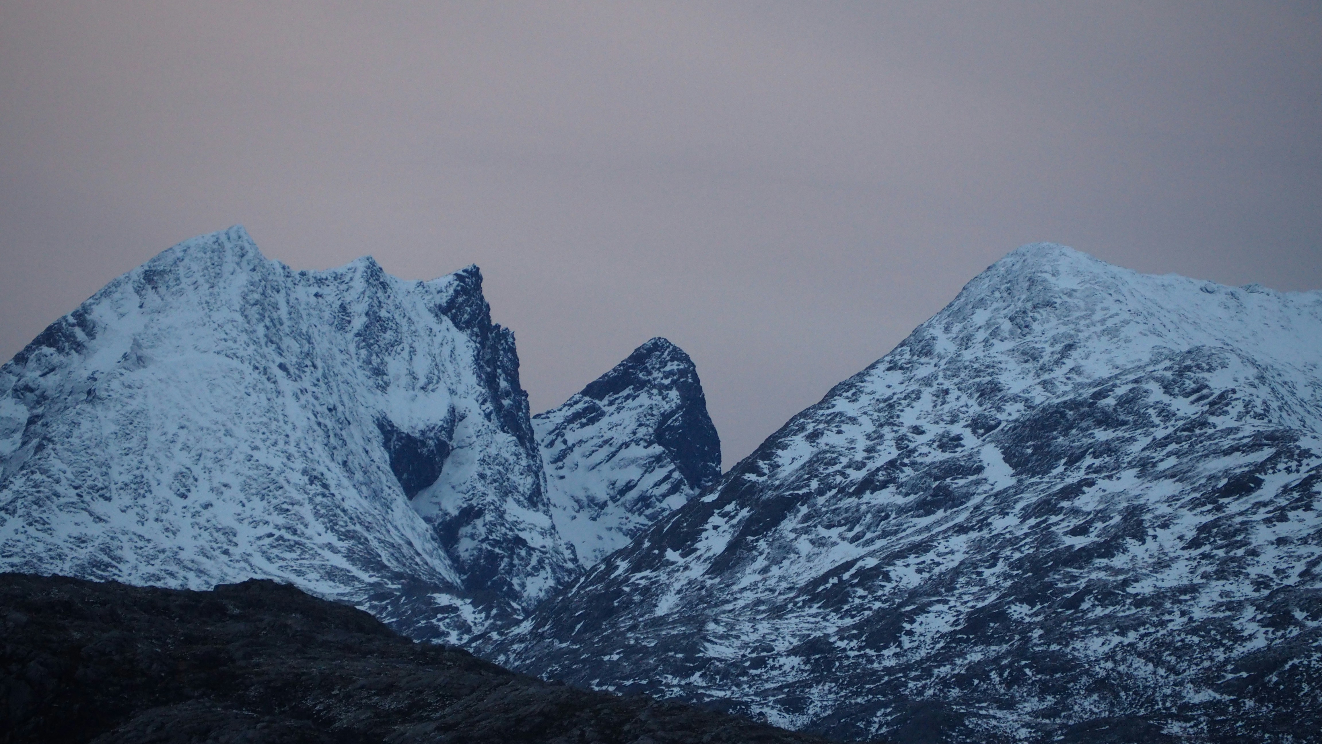 Snow-covered mountains under a dusky sky