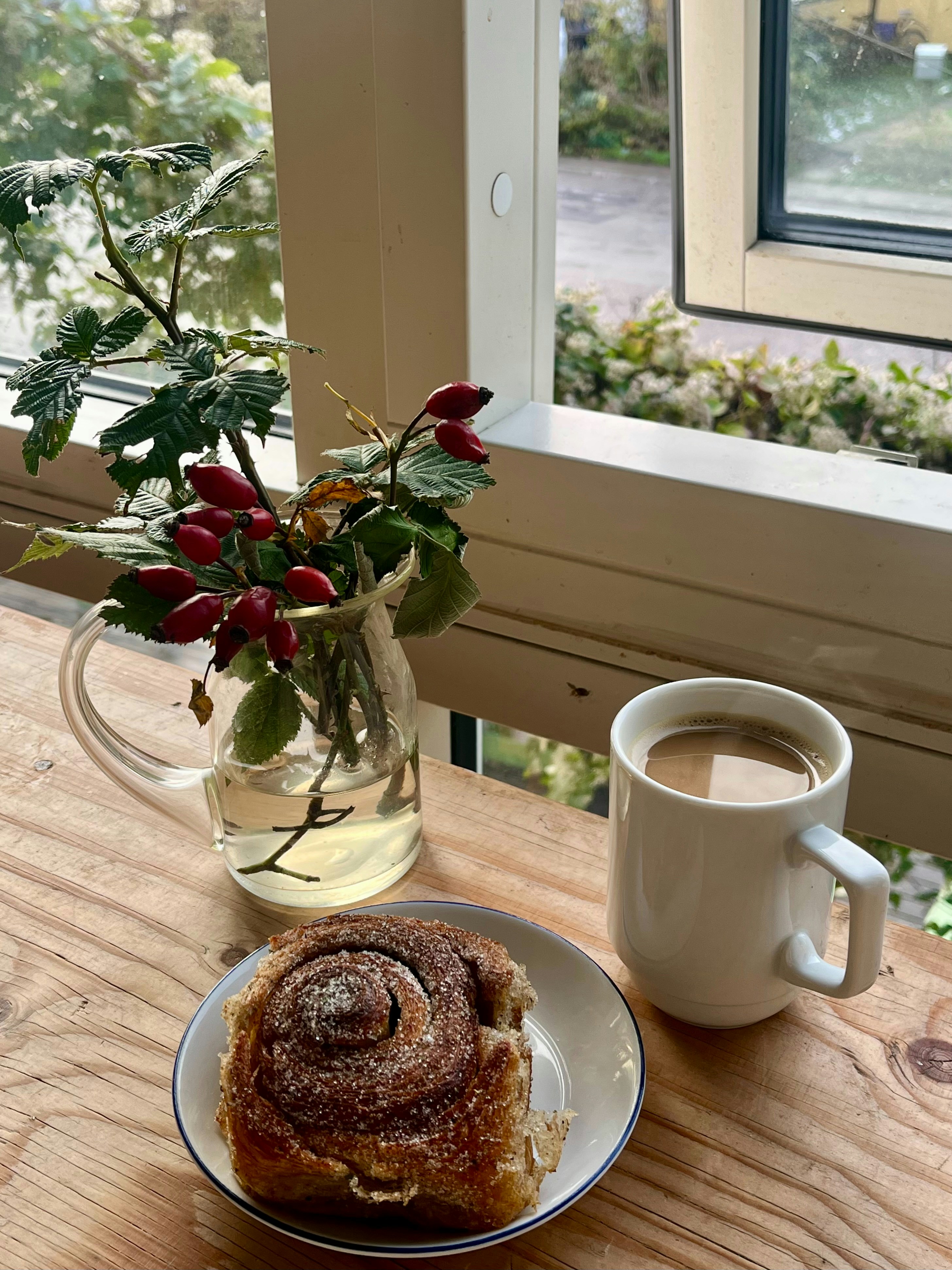 シナモンロールにコーヒーとローズヒップの枝を添えて。