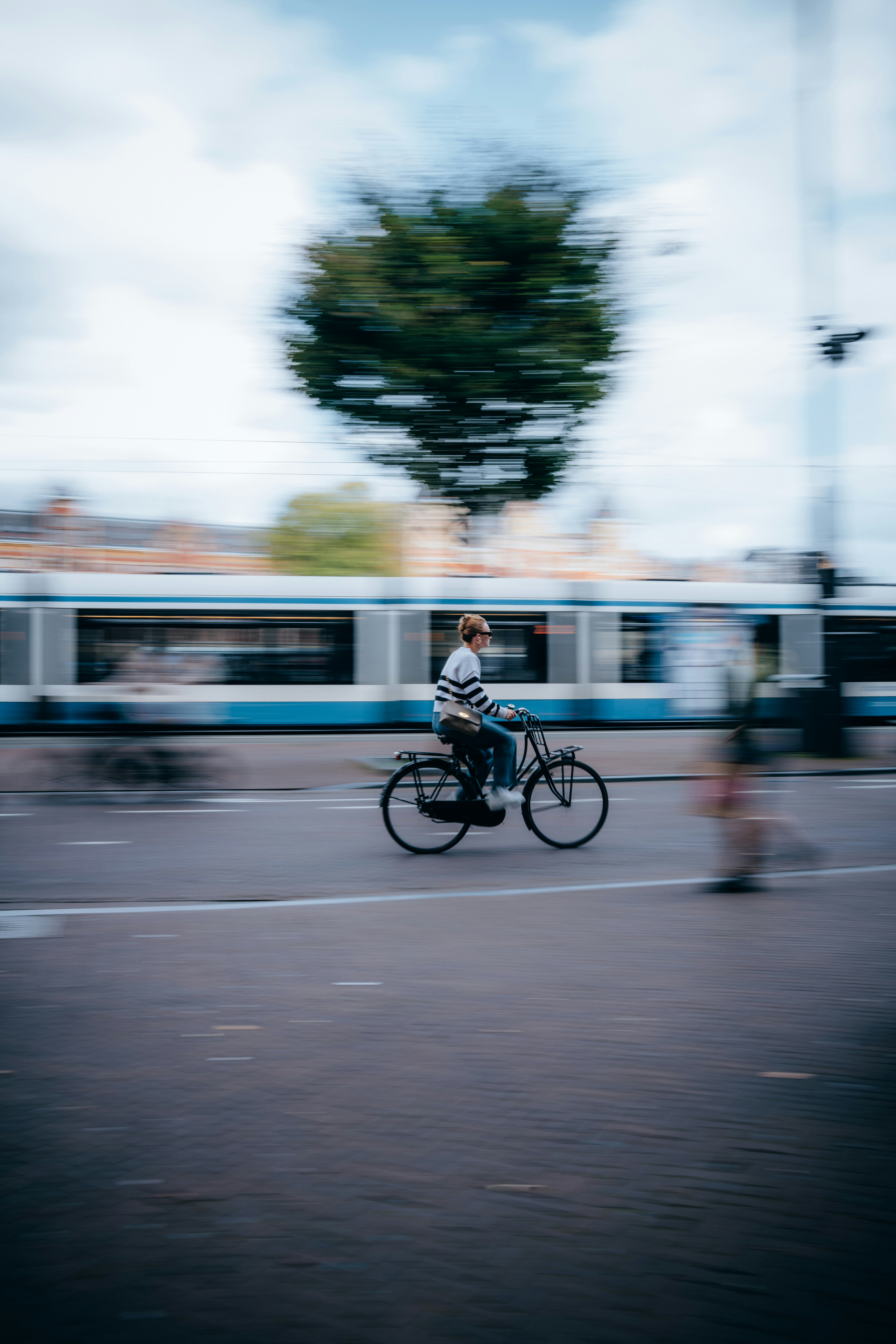 Person cycling past a tram with blurred motion
