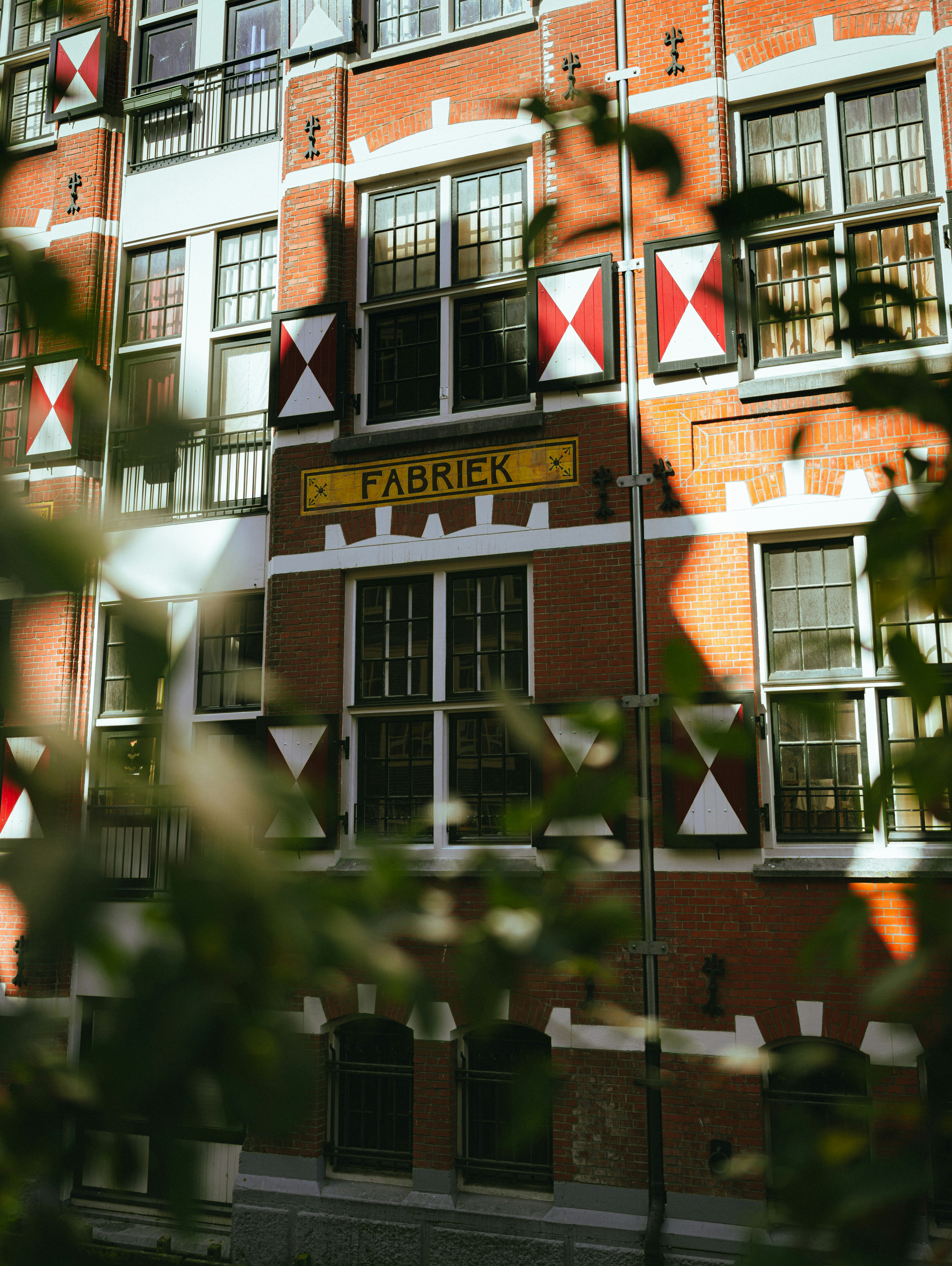Brick building with patterned shutters and "fabriek" sign.