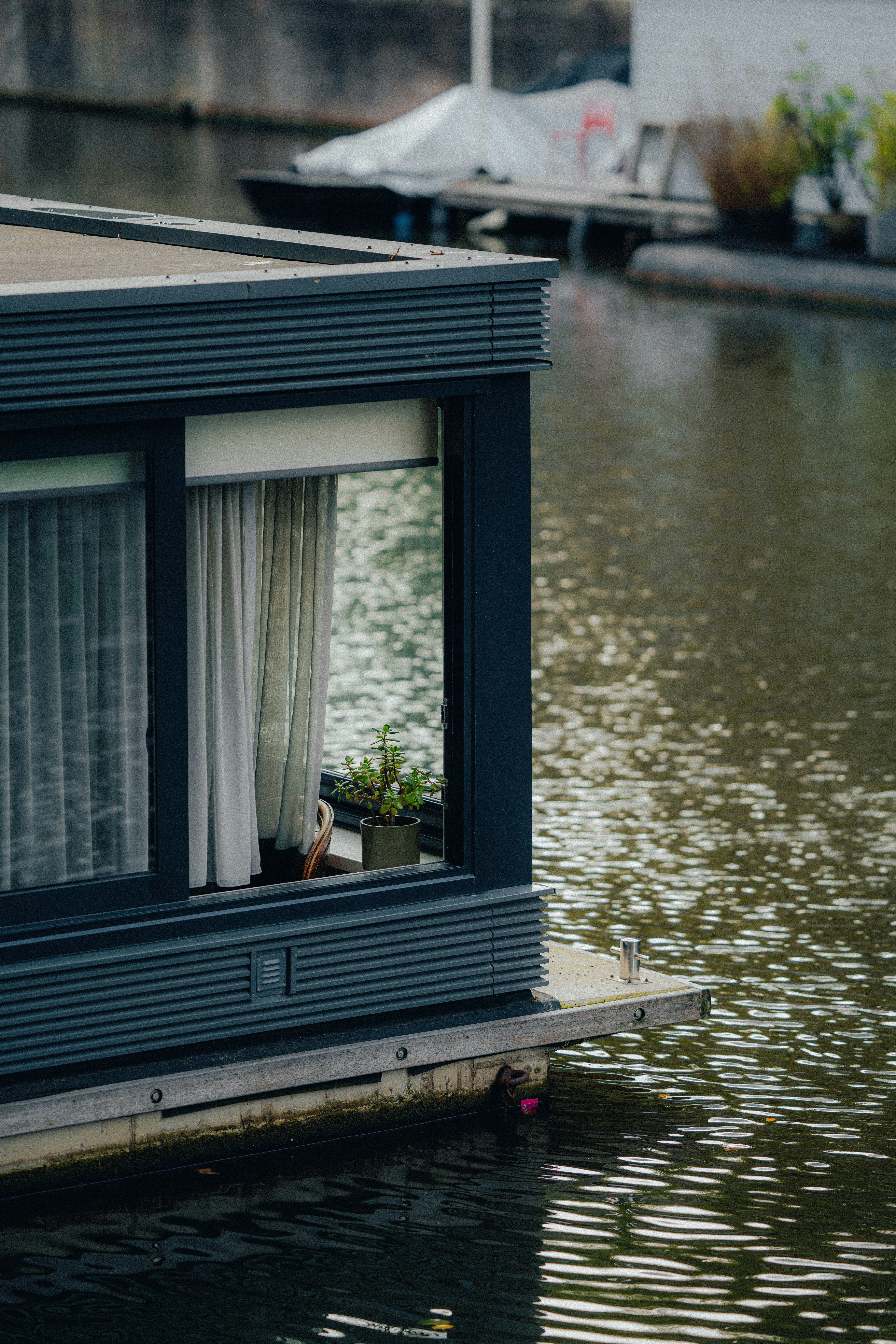 Modern houseboat docked on a calm canal waterway.