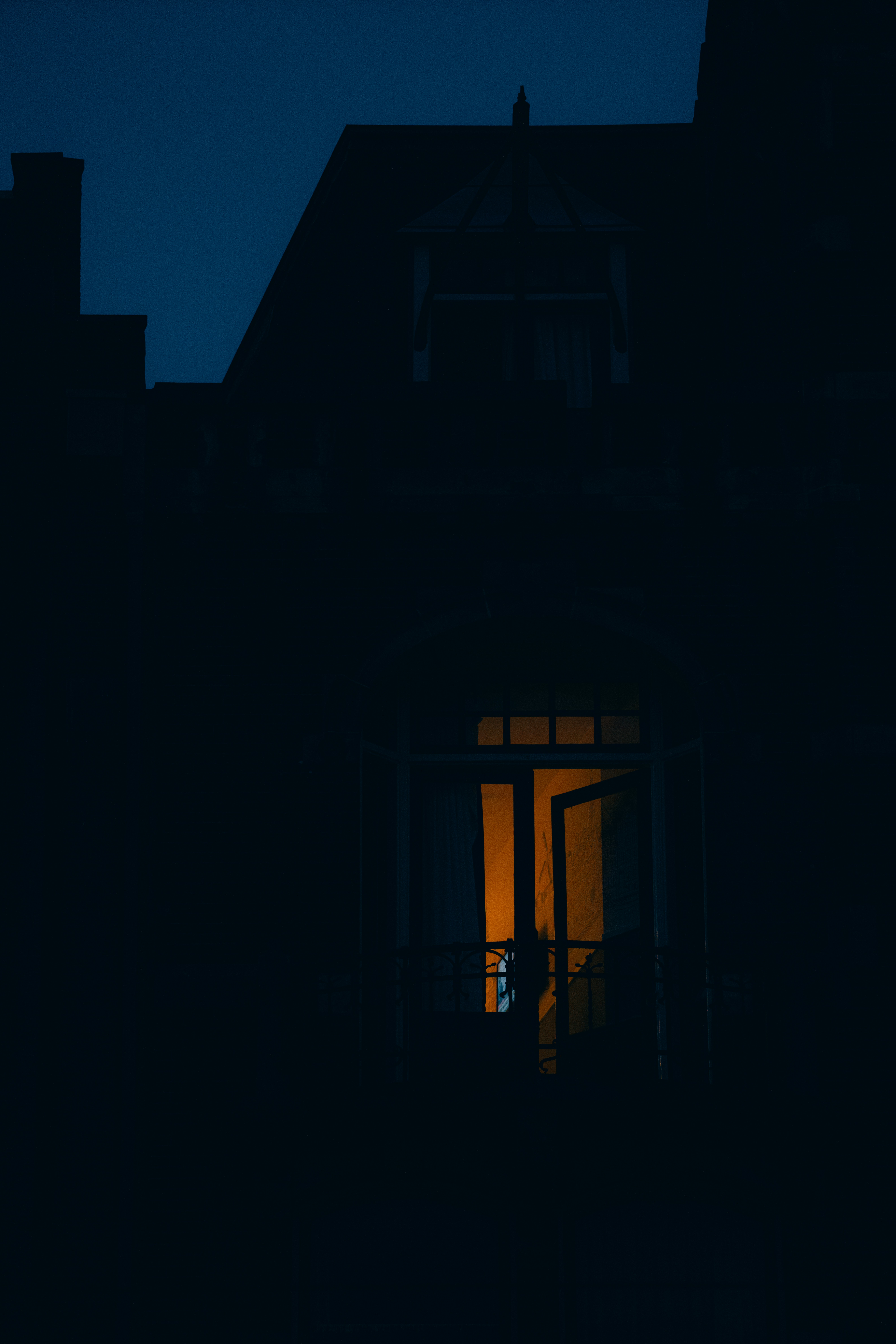 A dimly lit window glows warmly at dusk.