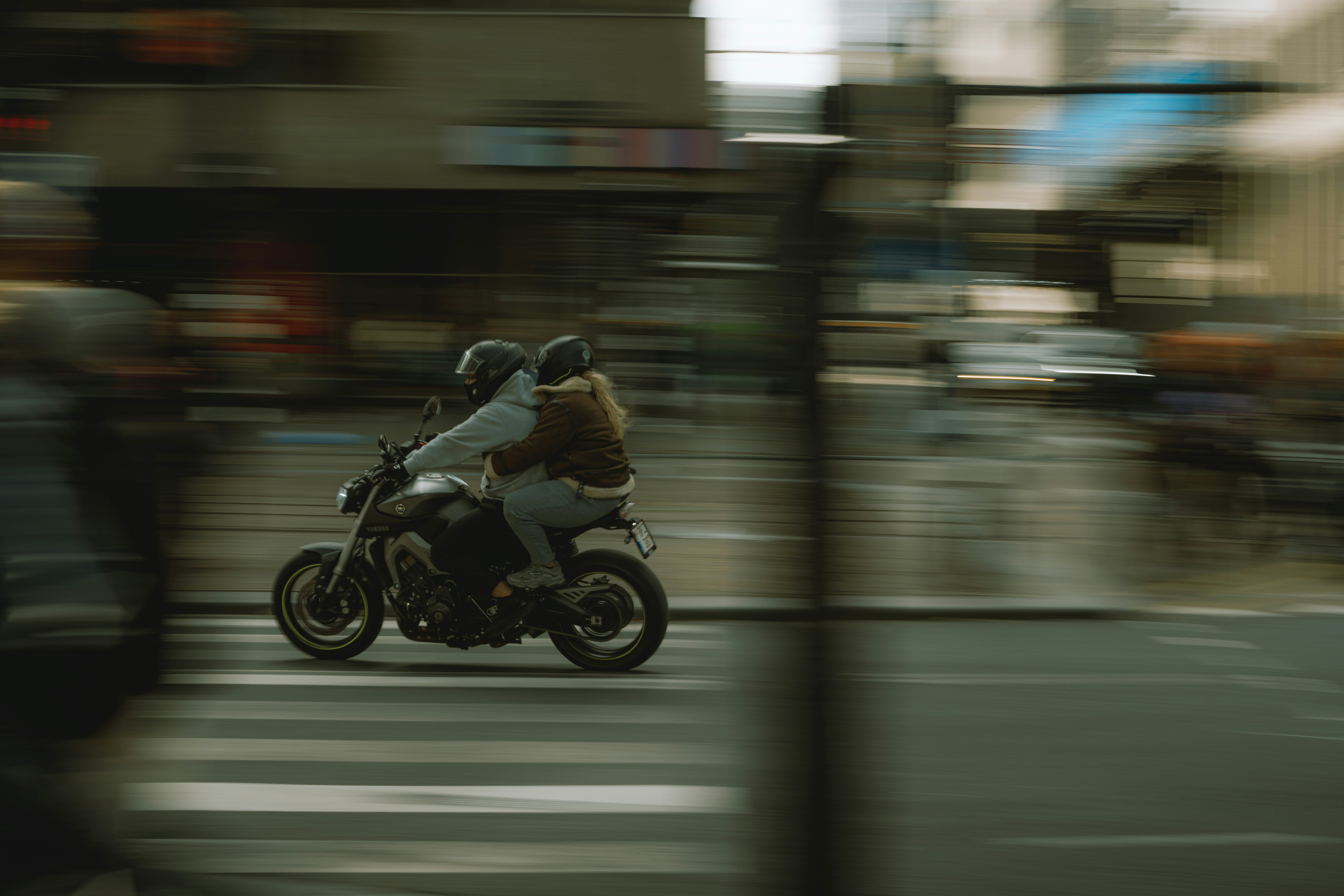 Two people riding a motorcycle through city streets