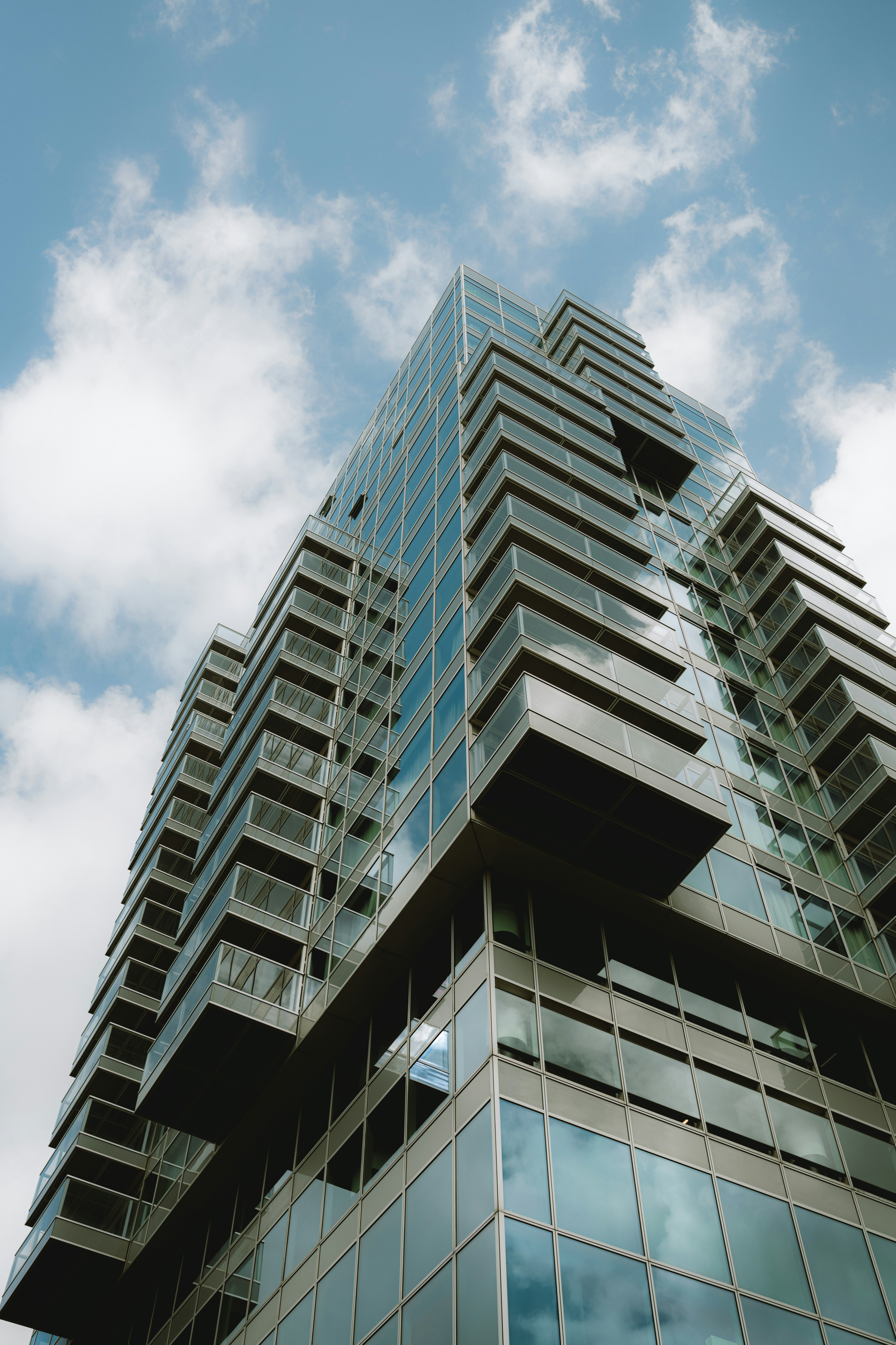 Modern glass skyscraper against a cloudy blue sky