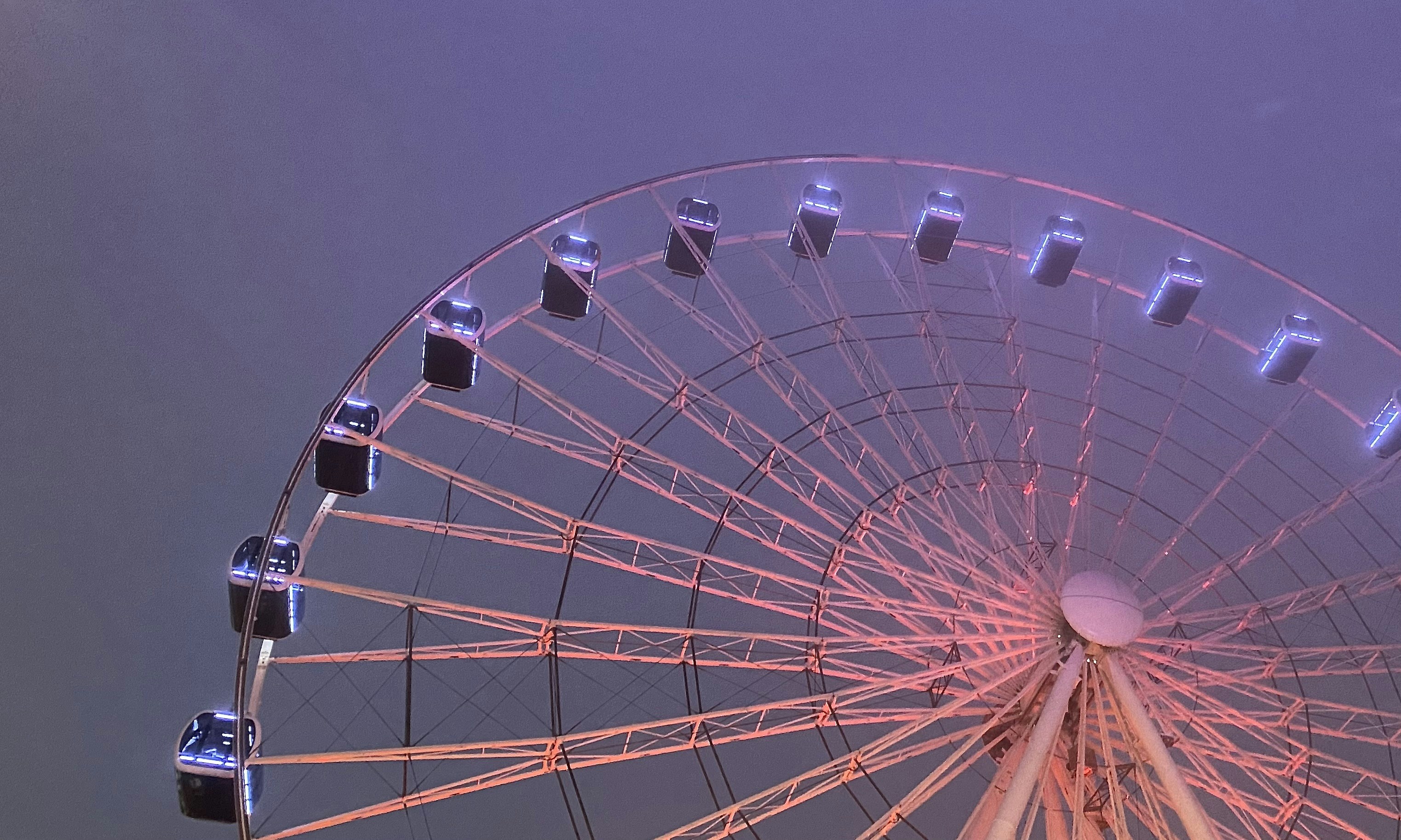 A ferris wheel illuminated at dusk with purple sky