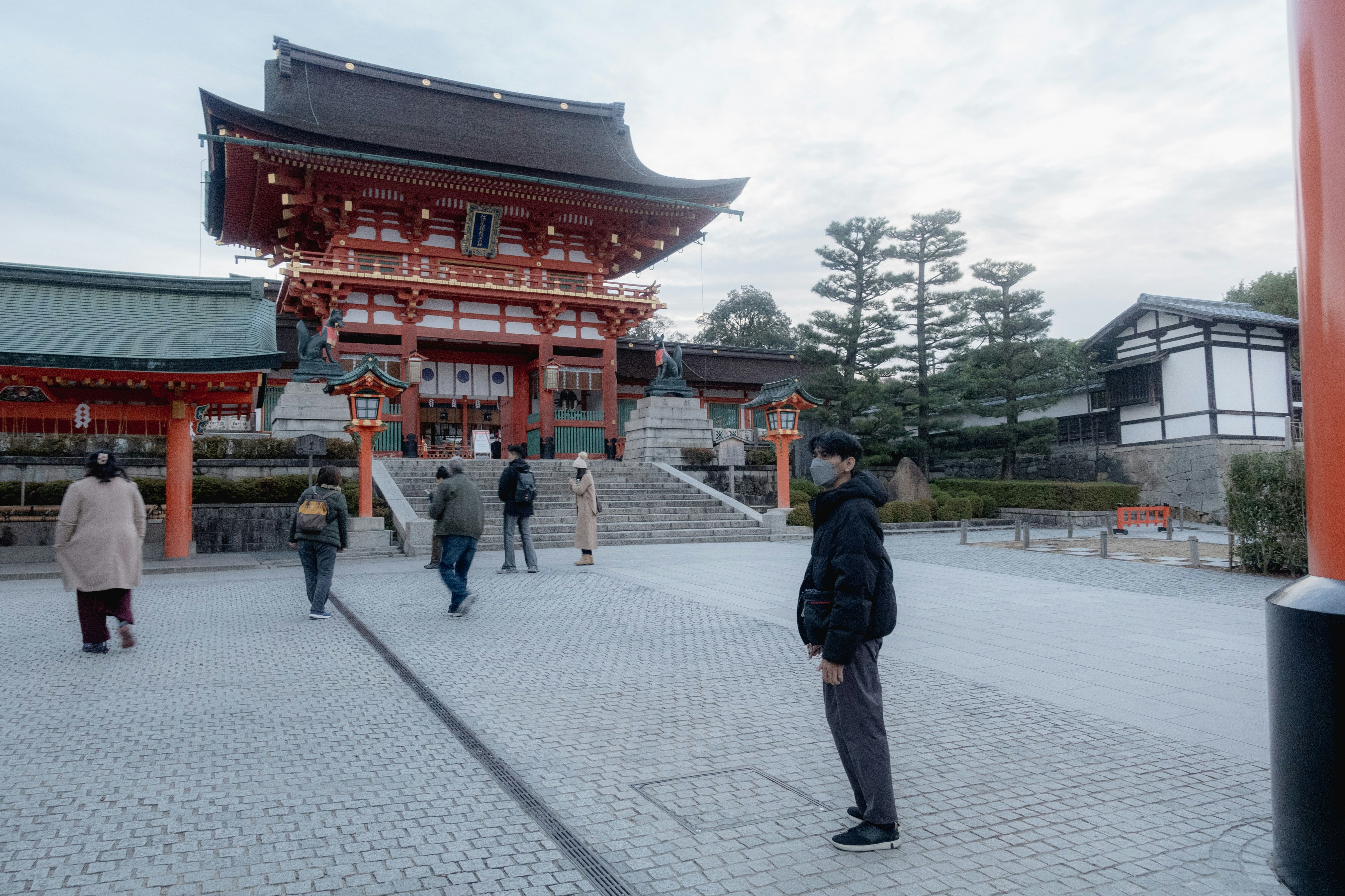 People walking near a traditional japanese temple entrance.