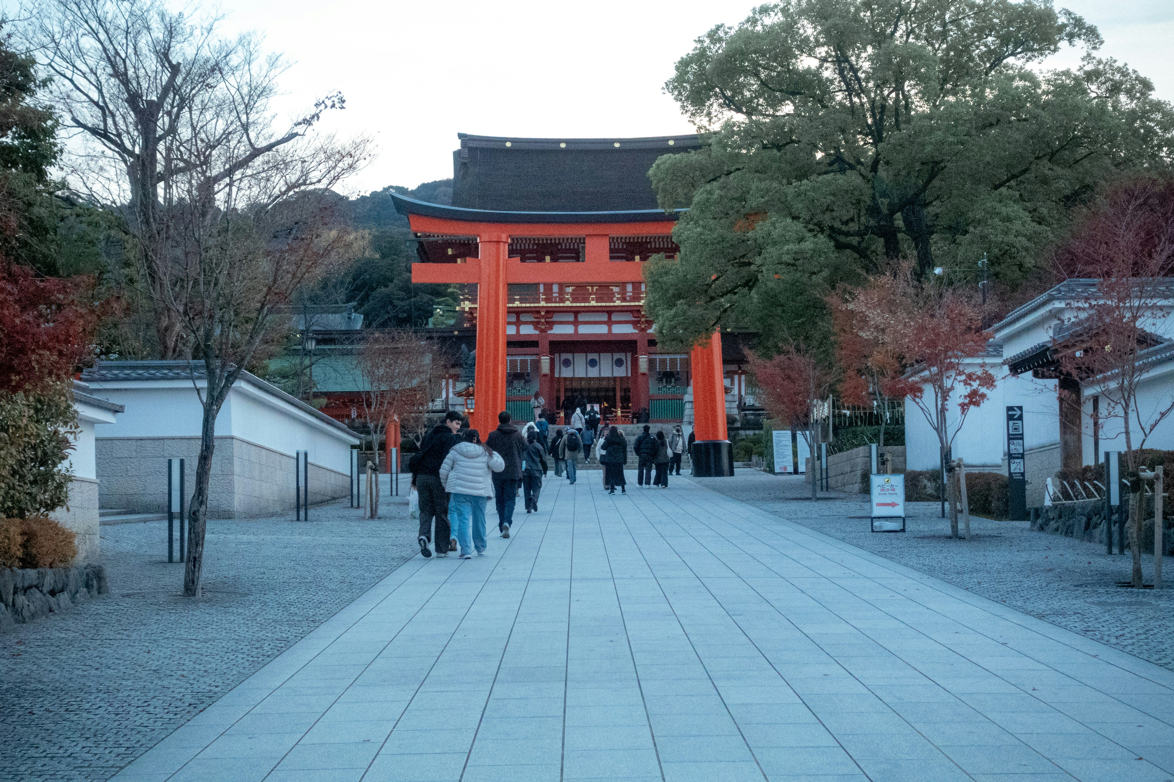 People walk towards a large orange torii gate.