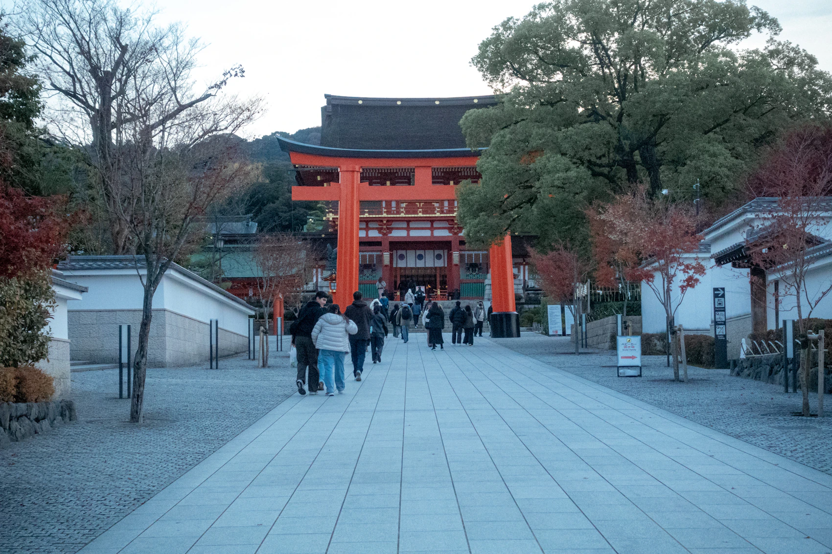 Visitors approaching a vermilion torii gate at Fushimi Inari in Kyoto