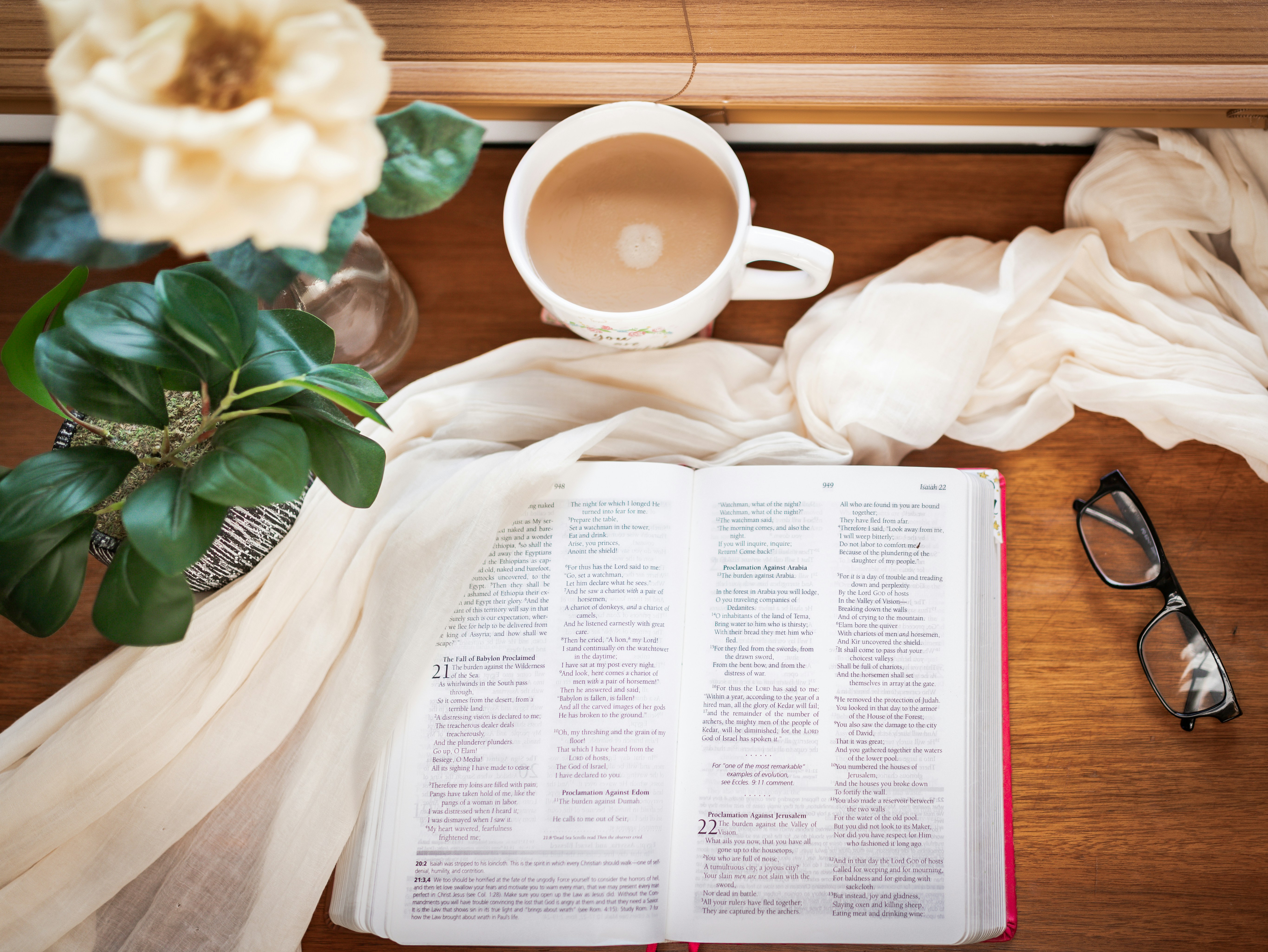 Open book with coffee and glasses on table.