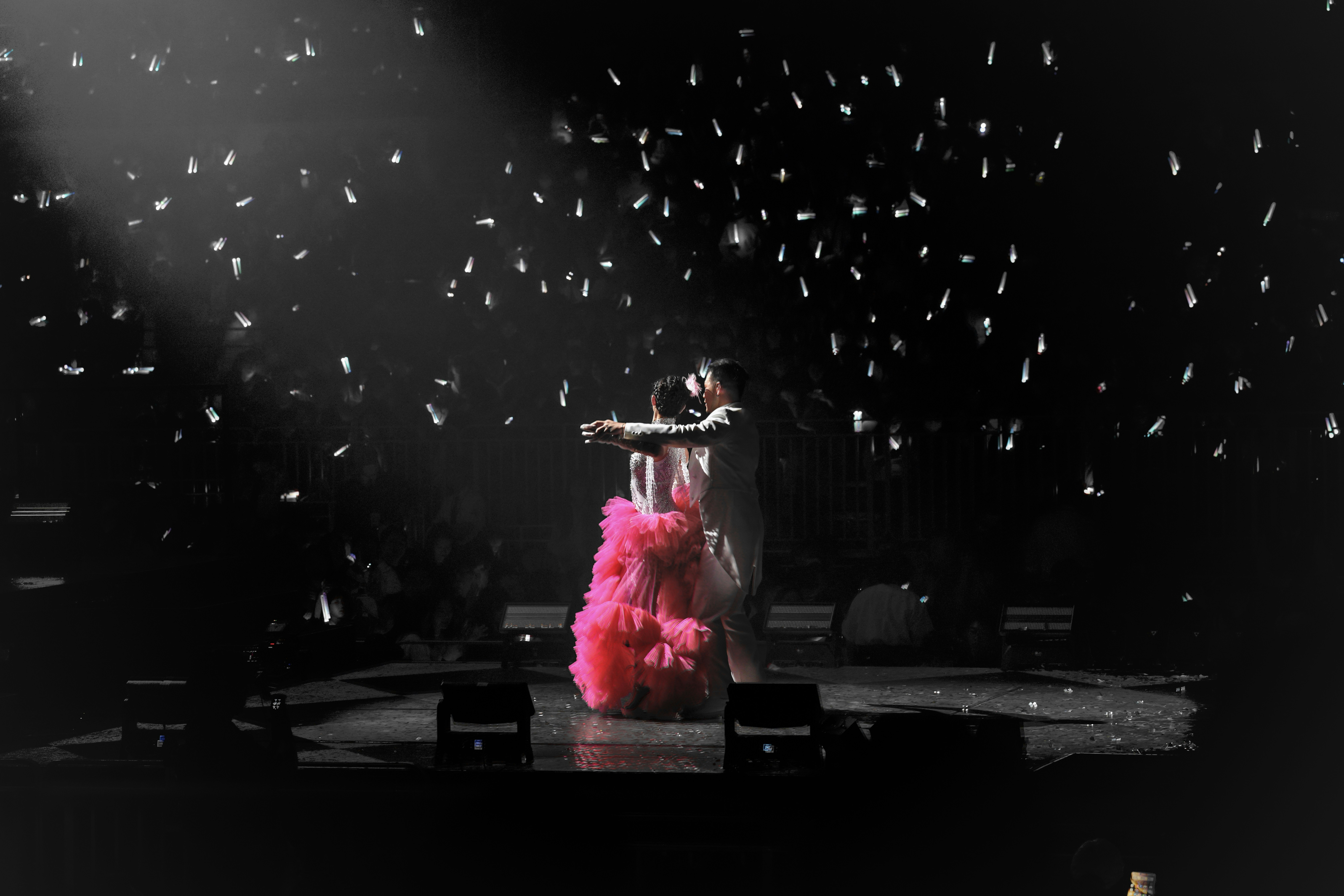 Singer in pink dress performing on stage with confetti.